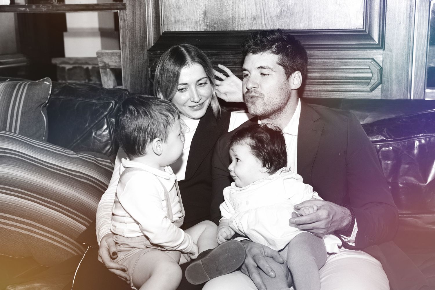 A vintage black and white photograph showing a family of four sitting together in what appears to be a car interior.
