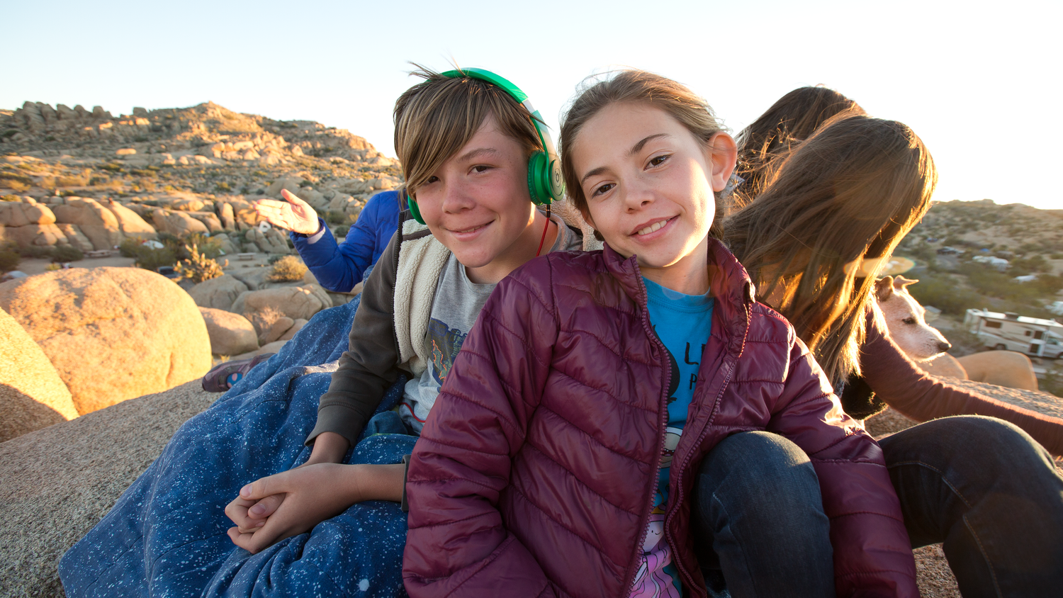 Group of friends enjoying sunset together on rocky terrain during outdoor adventure.