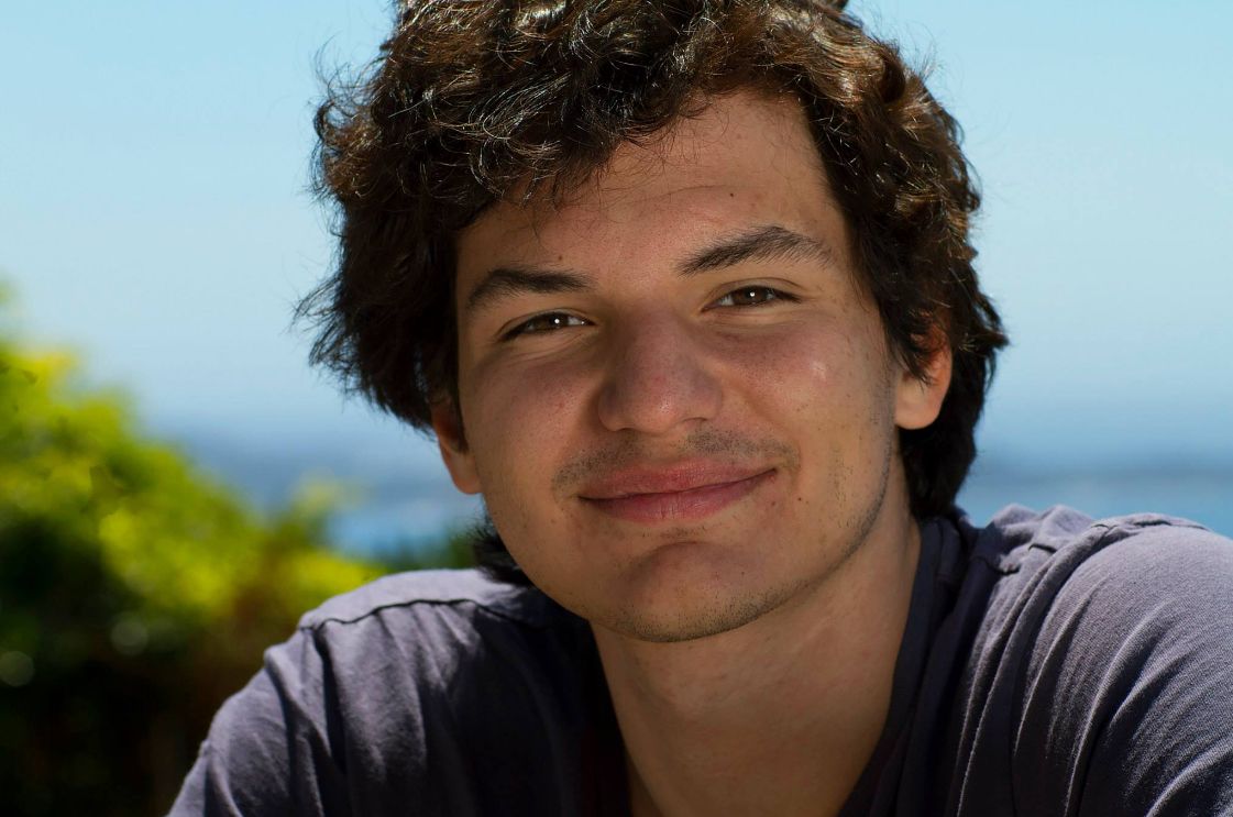 Casual outdoor portrait with natural lighting and blue sky background.