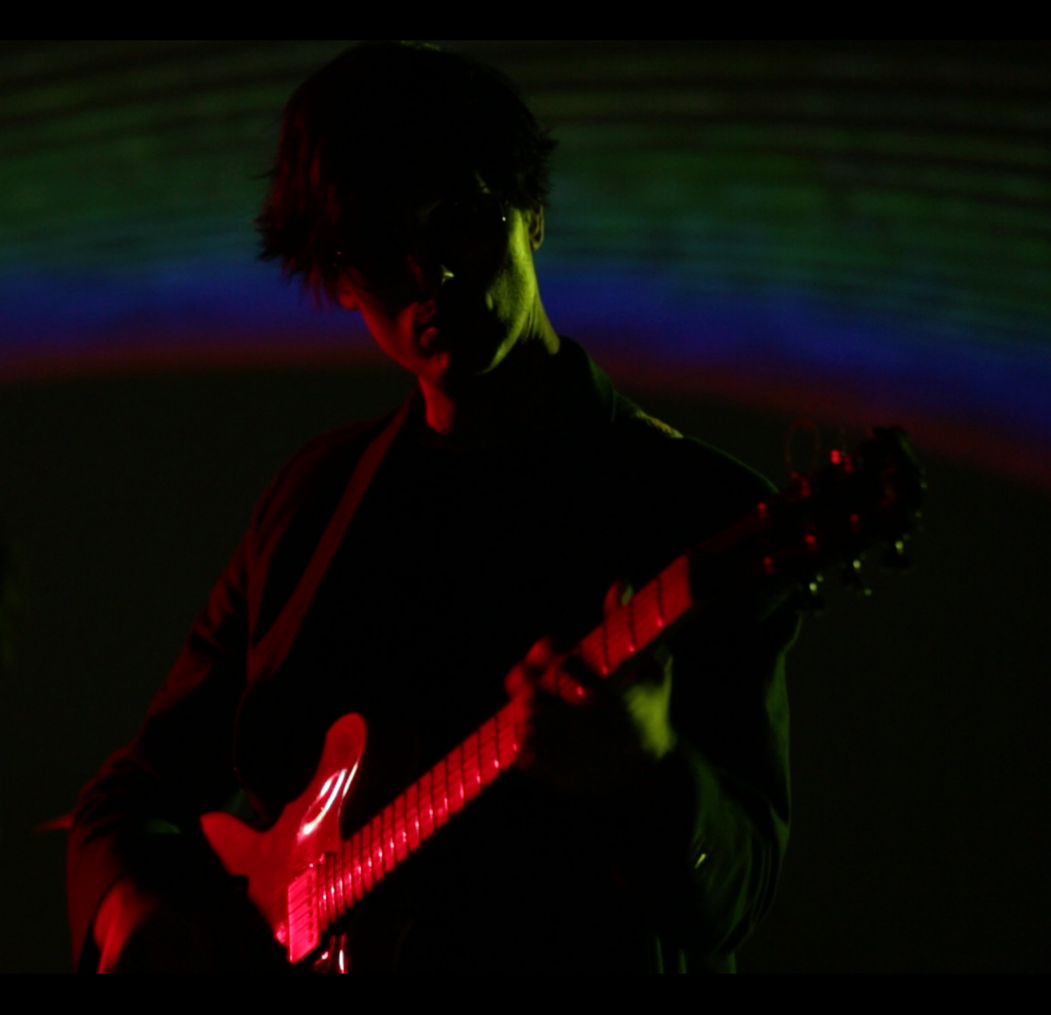 Musicians performing on stage illuminated by striking red and yellow lighting effects.