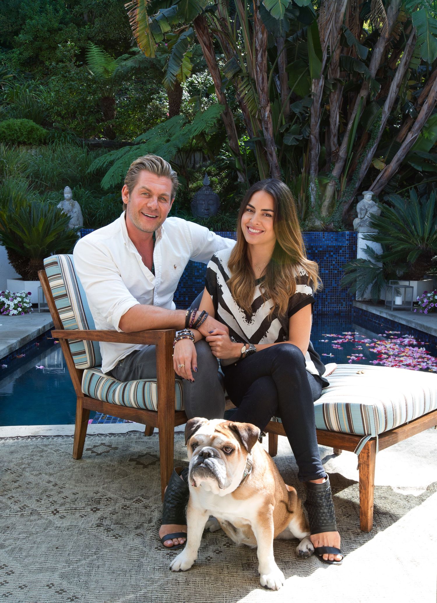 Couple relaxing on outdoor patio furniture with bulldog.