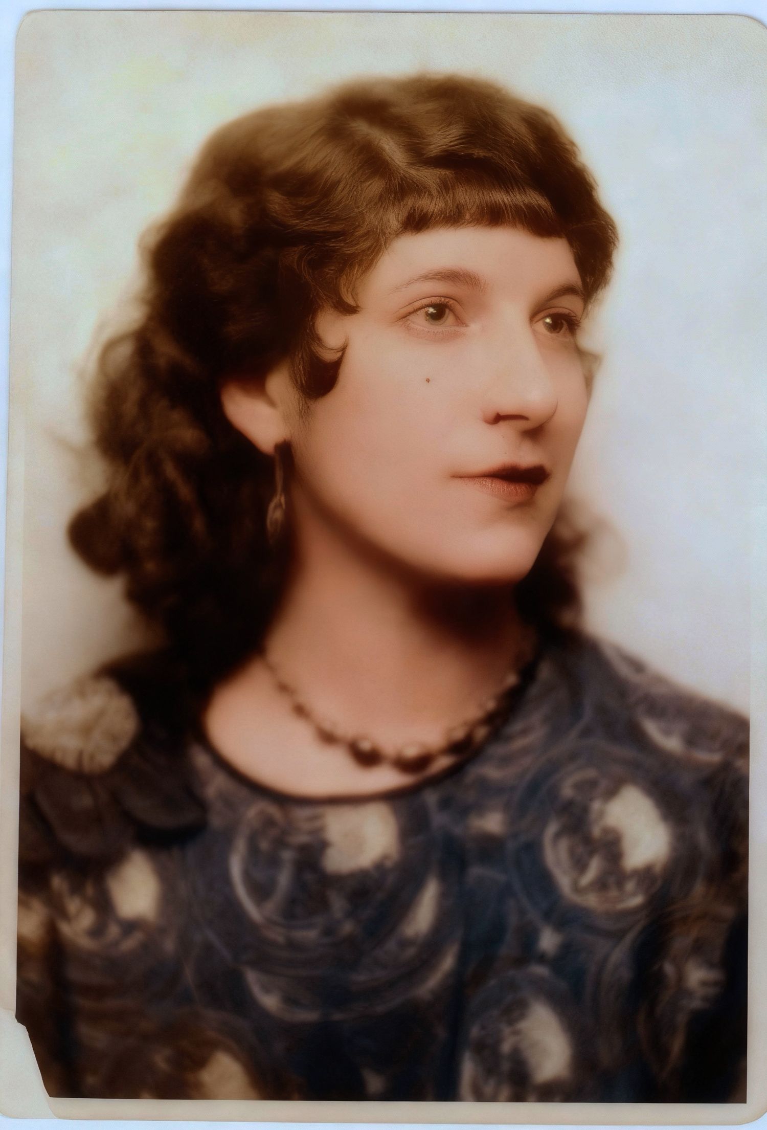 A vintage photo strip shows four sequential sepia-toned portraits of a person wearing a dark patterned top and beaded necklace.