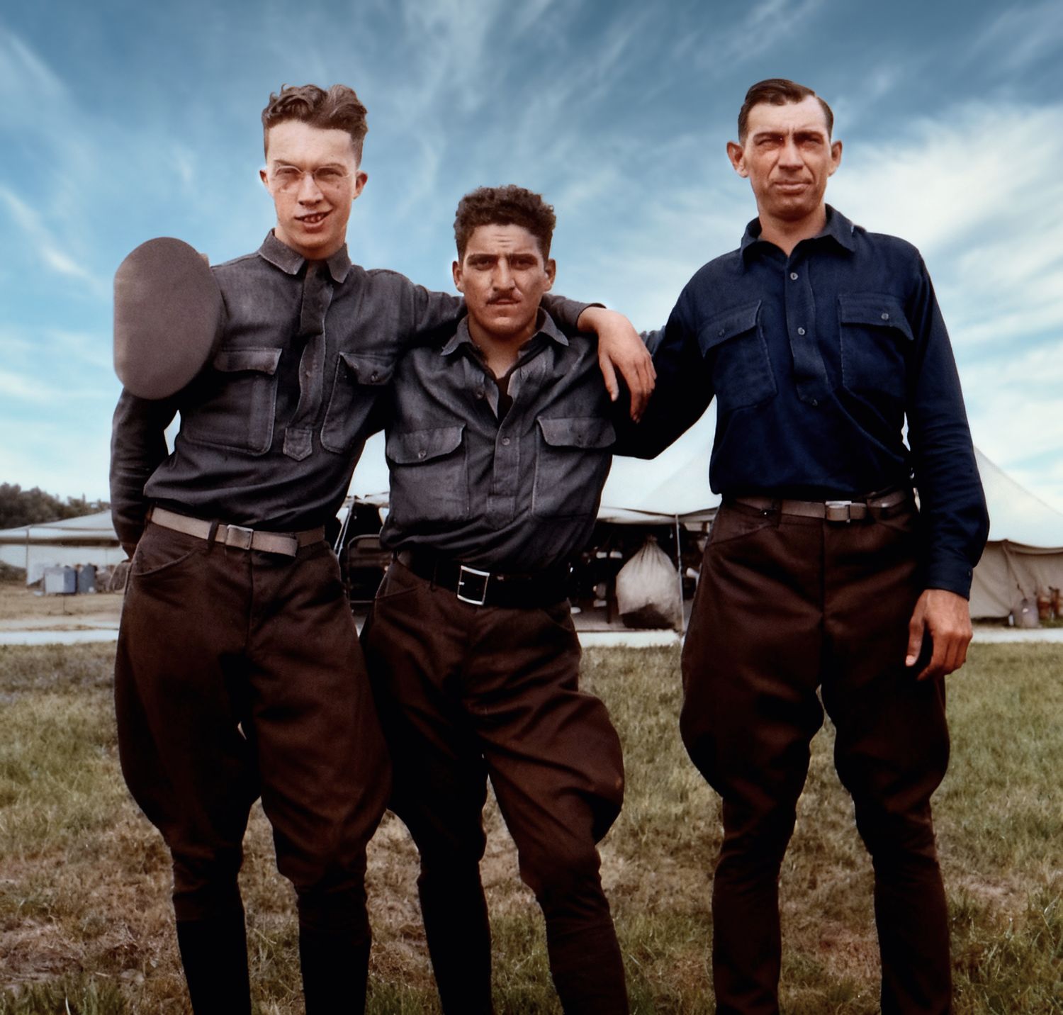 A group of men in dark workwear stand together in a line against a dramatic cloudy sky in a rural setting.