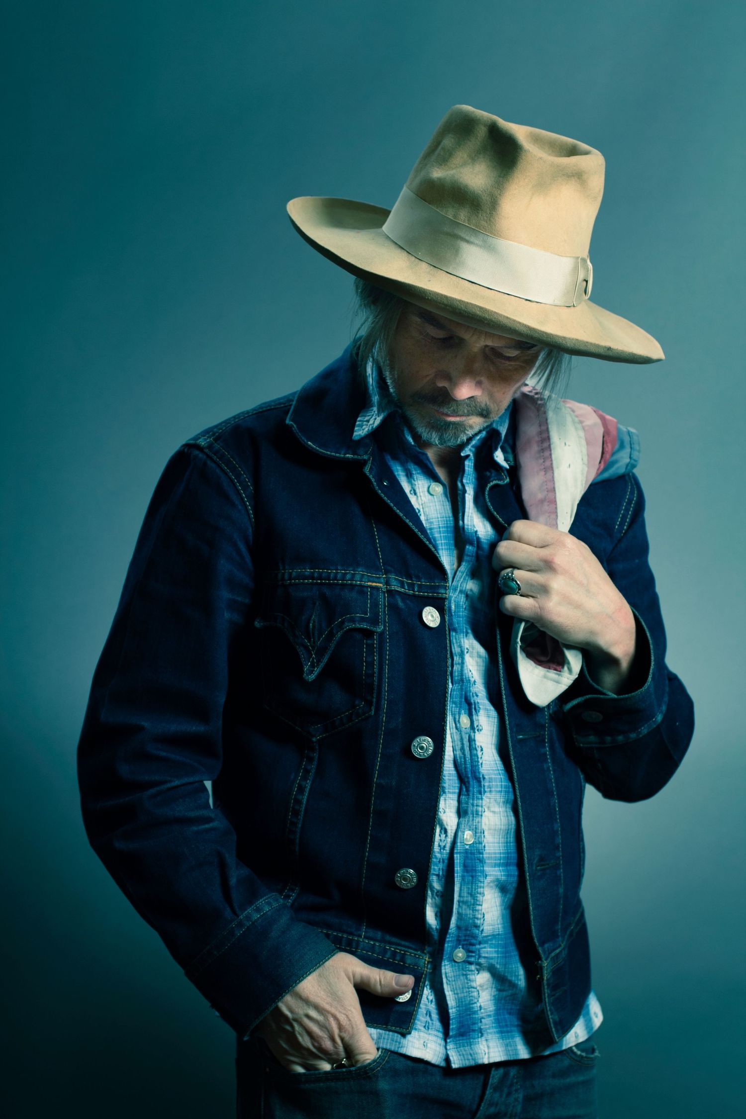 Dramatic portrait series with person in denim jacket and hat against teal background.