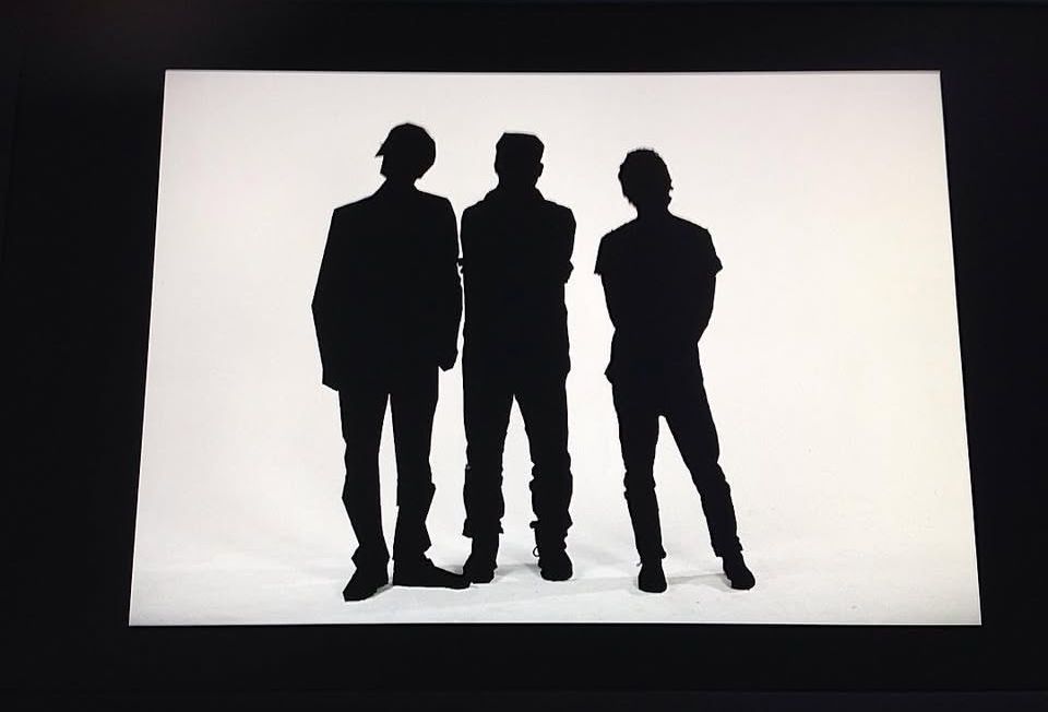 Silhouettes of three people standing against a white background.