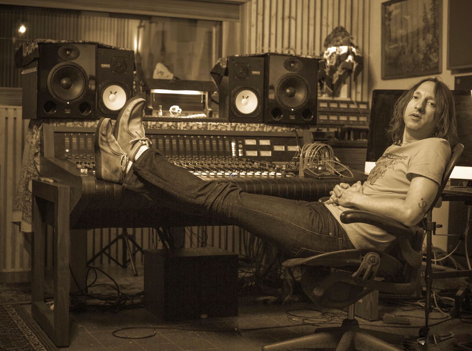 Professional recording studio with mixing console and equipment in sepia tones.