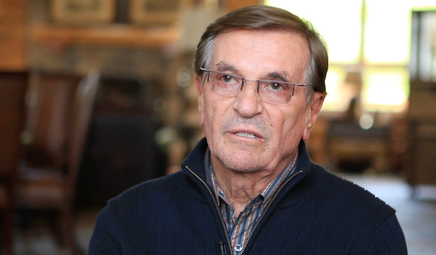 A series of five similar photos showing someone in glasses and a dark jacket sitting in what appears to be an interview setting.