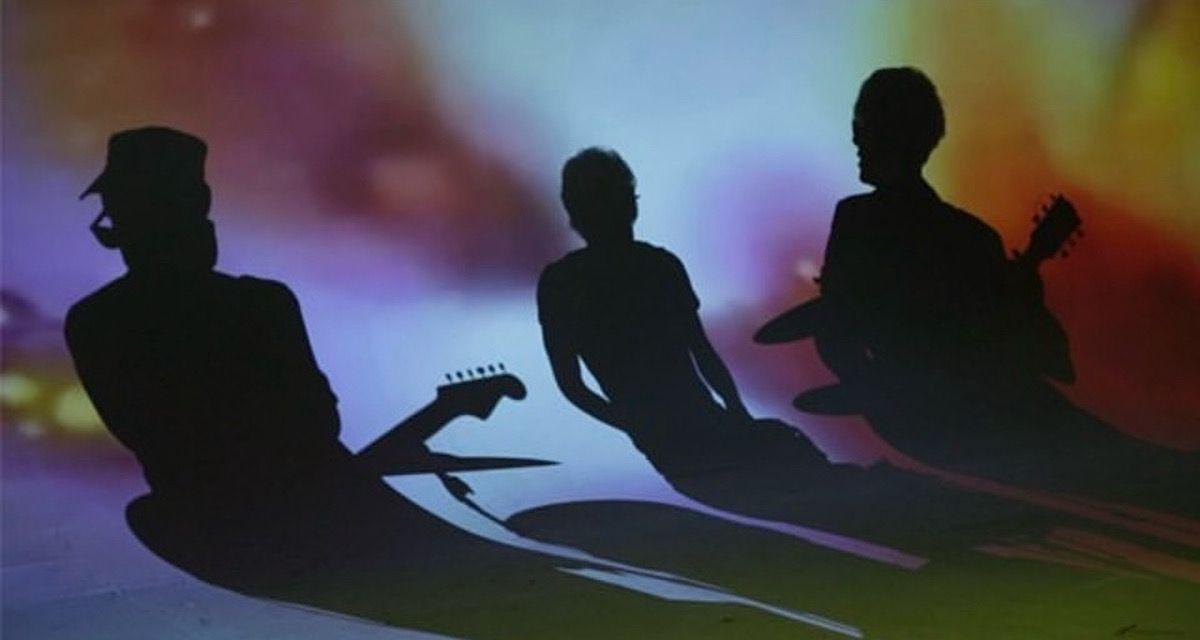 Silhouettes of band members performing against colorful stage lighting.