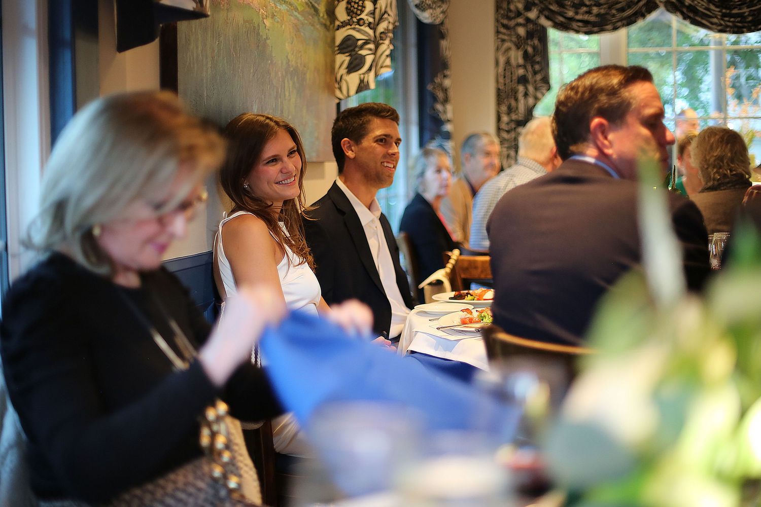 Formal dining event with guests seated at decorated tables in an upscale venue.
