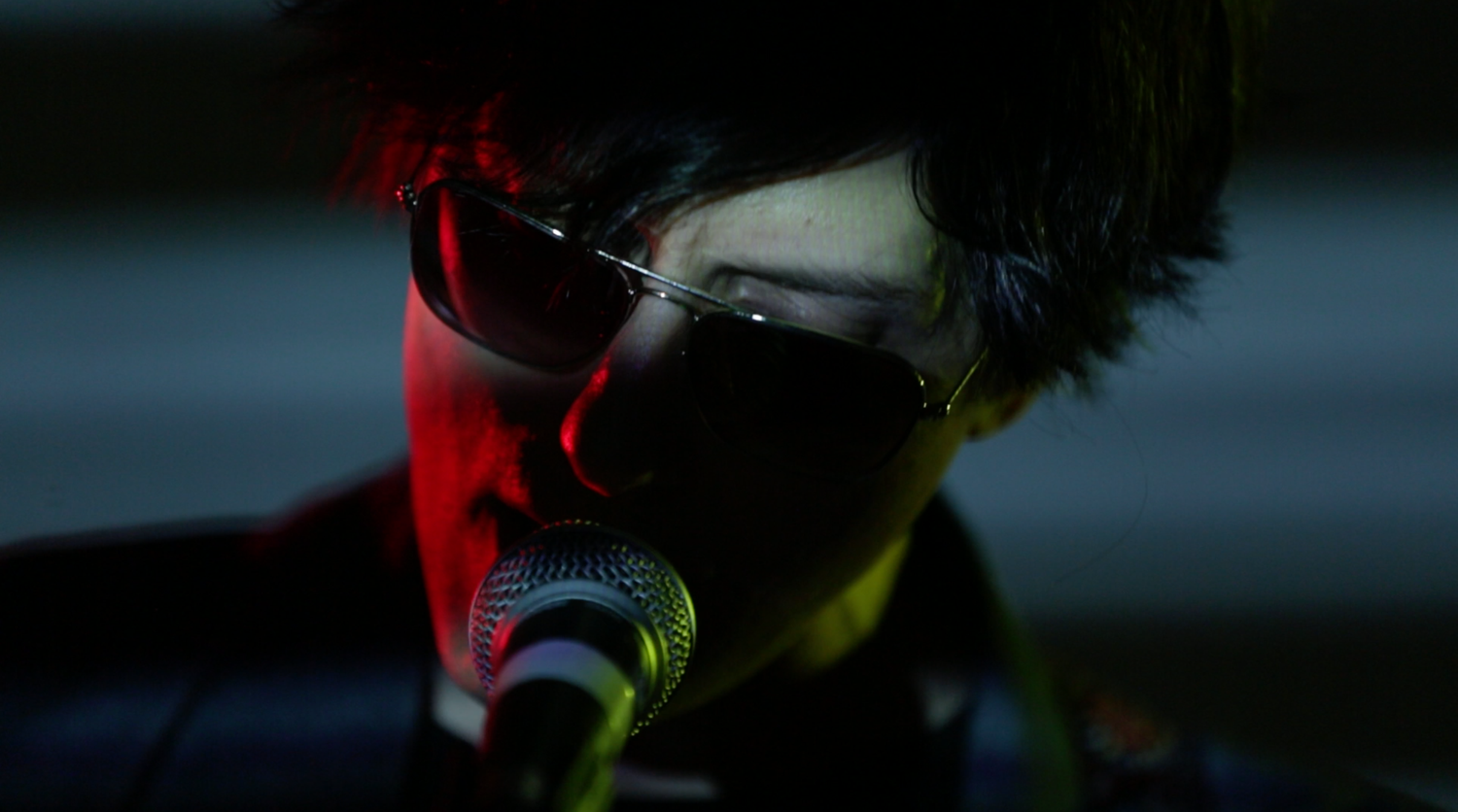 Musicians performing on stage with dramatic colored lighting and silhouettes.