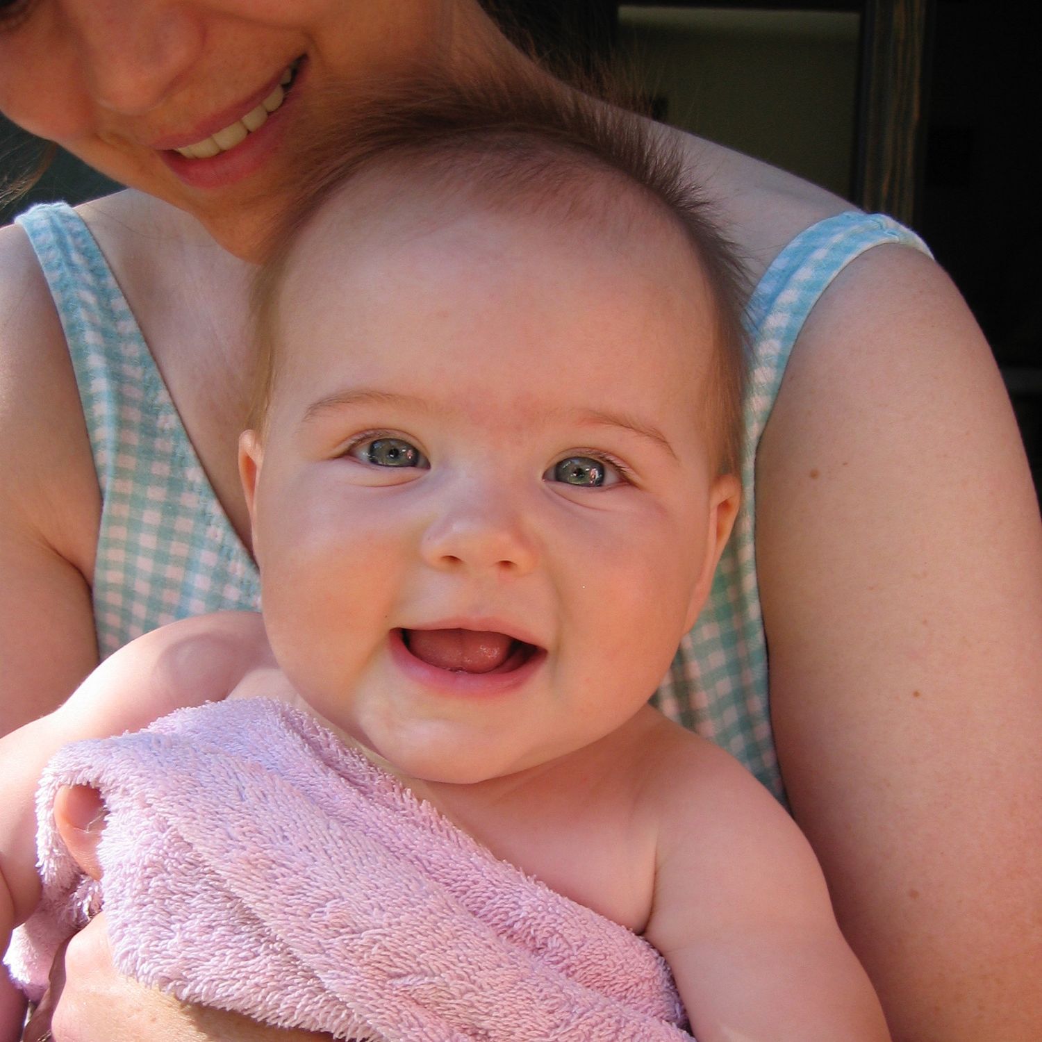 A series of close-up photos showing a baby's joyful expressions while wearing a pink bib.