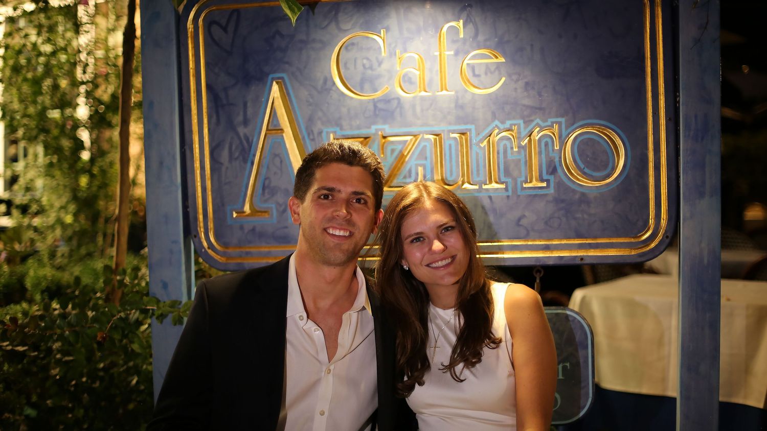 Illuminated cafe signage at night with decorative gold framing.