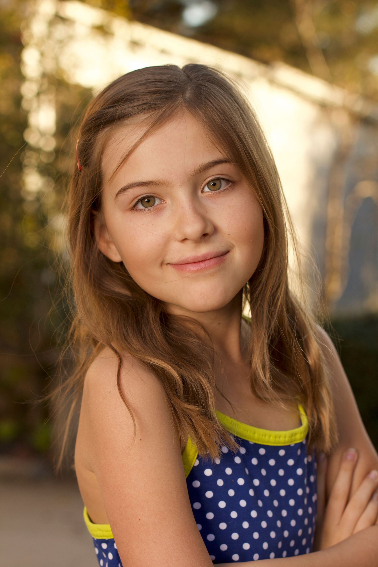 Young person in polka dot dress with neon trim poses outdoors in golden sunlight.