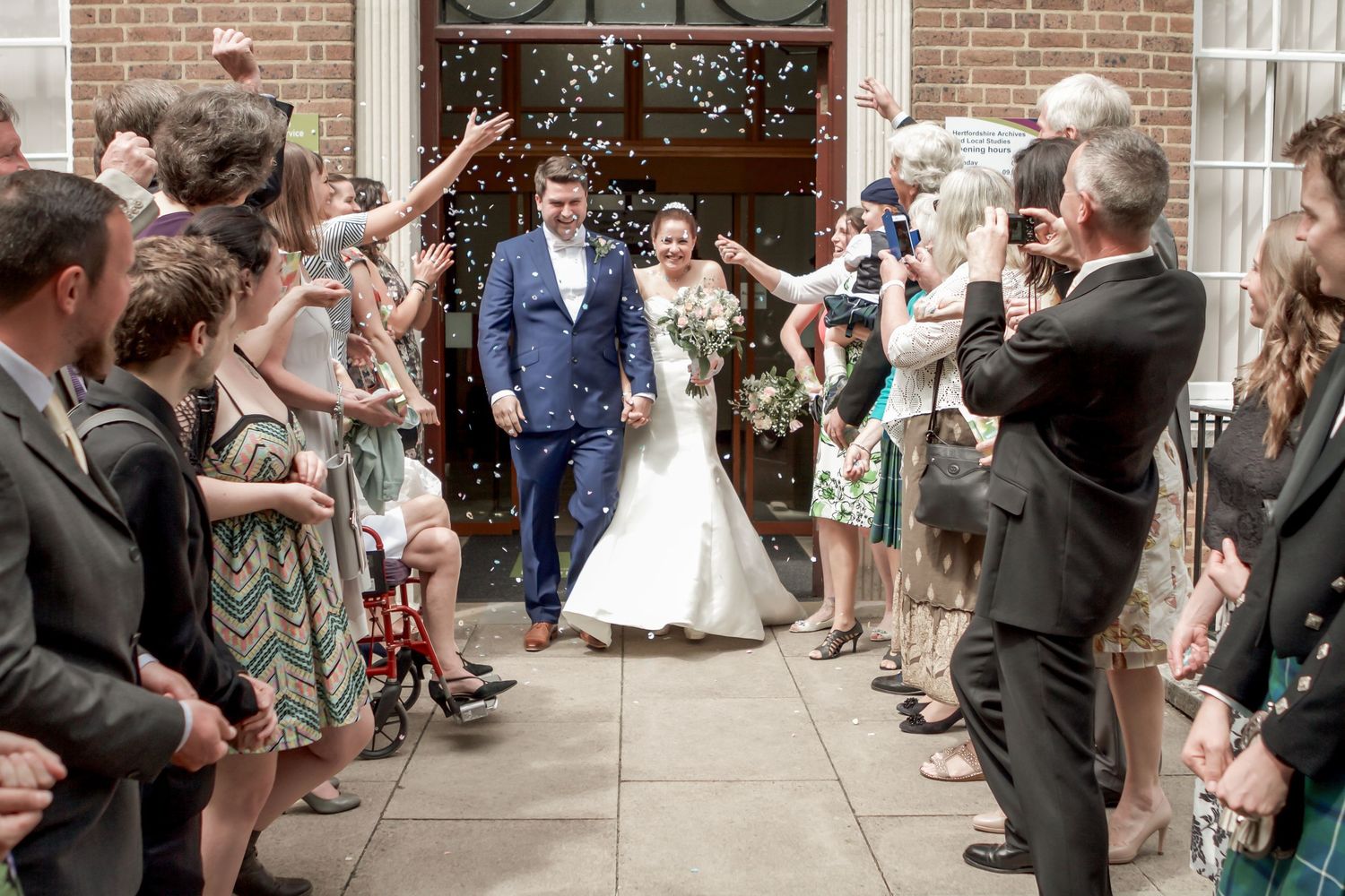 Guests cheering and throwing confetti at Surrey wedding ceremony exit. Wedding photographer, oliver charles photography
