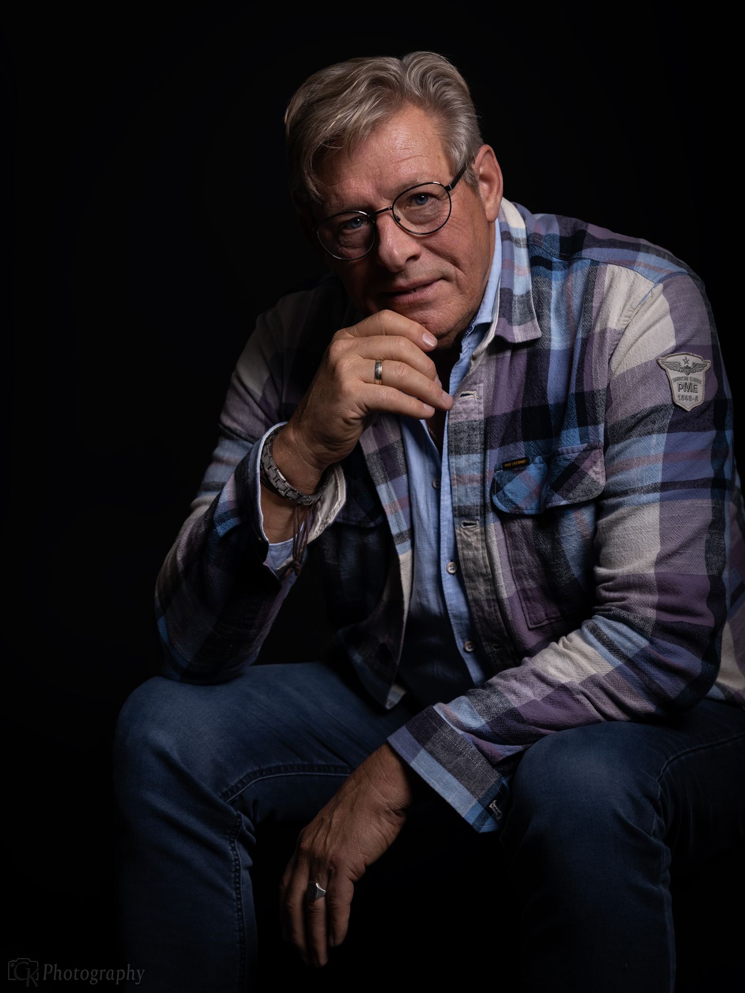 Krachtig studio portret van volwassen man met stijlvolle kleding tegen een donkere achtergrond met karaktervolle uitstraling