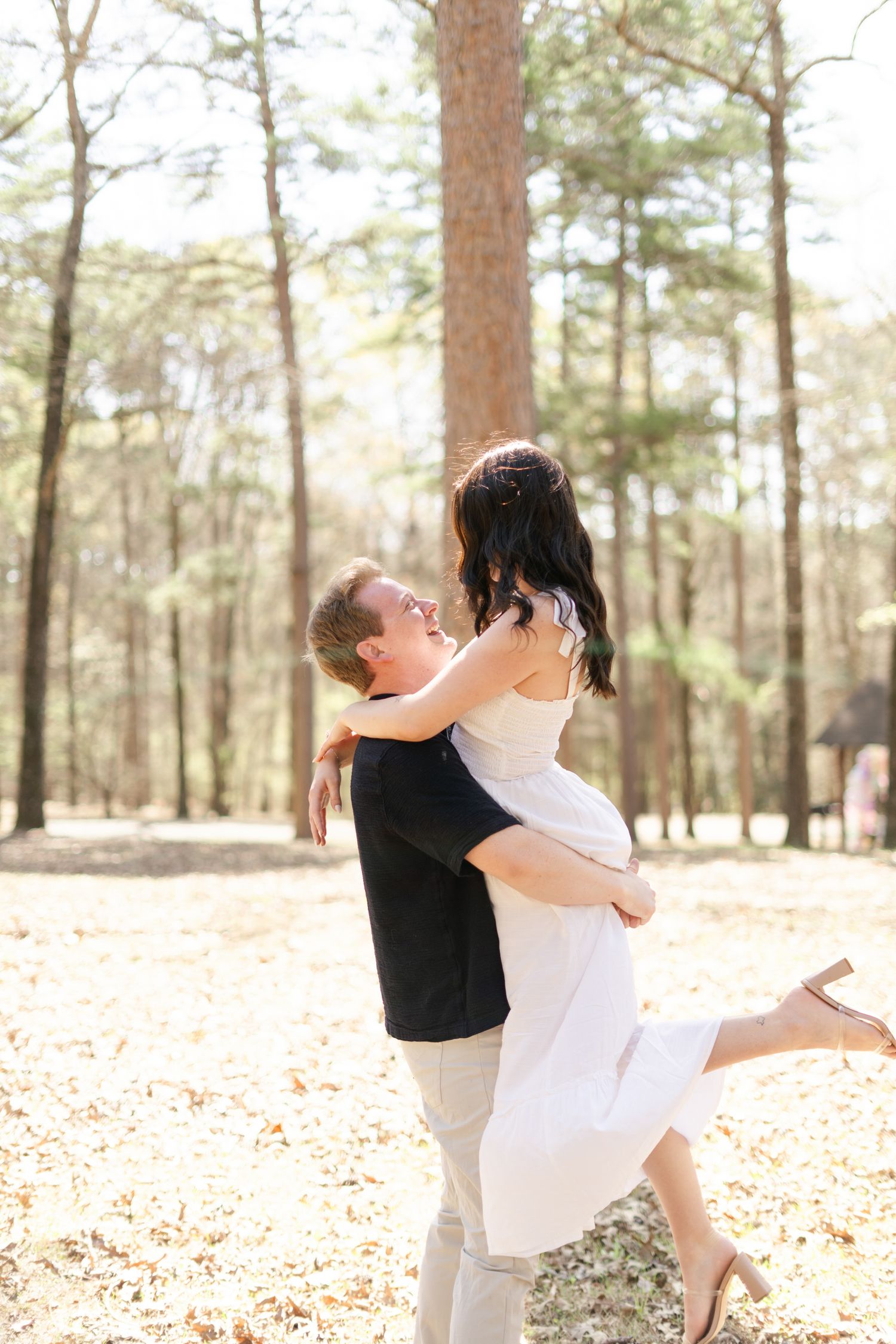 Dancing couple celebrates their wedding day among tall pine trees and fallen leaves.