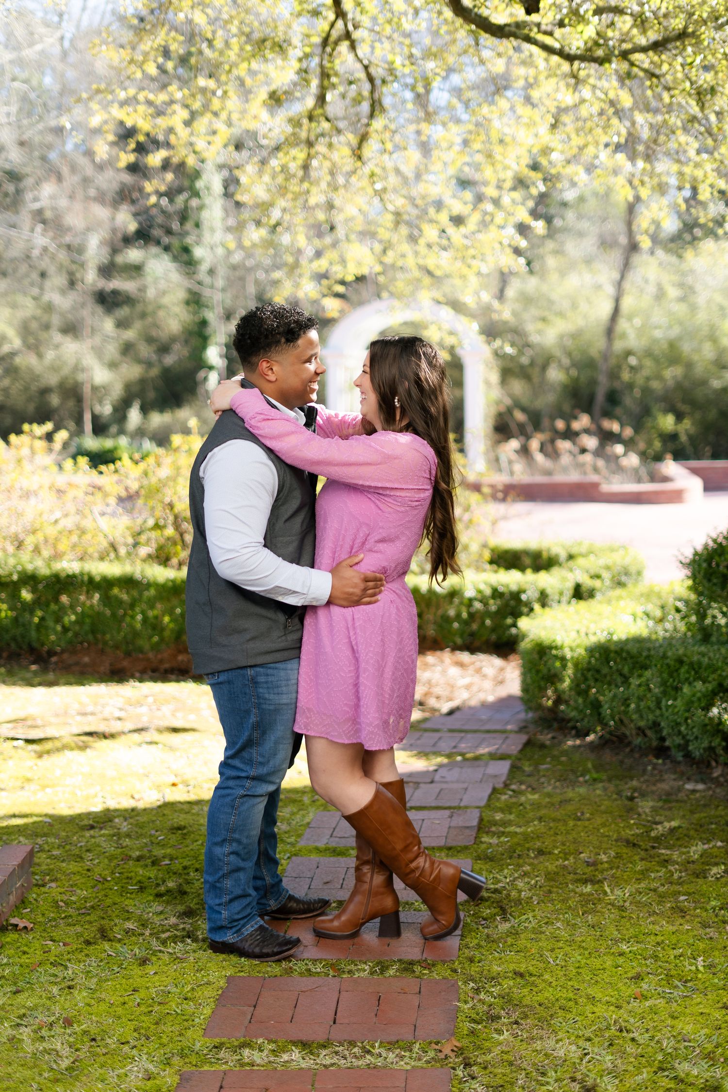 A couple shares a romantic moment on garden stepping stones surrounded by autumn foliage and greenery.