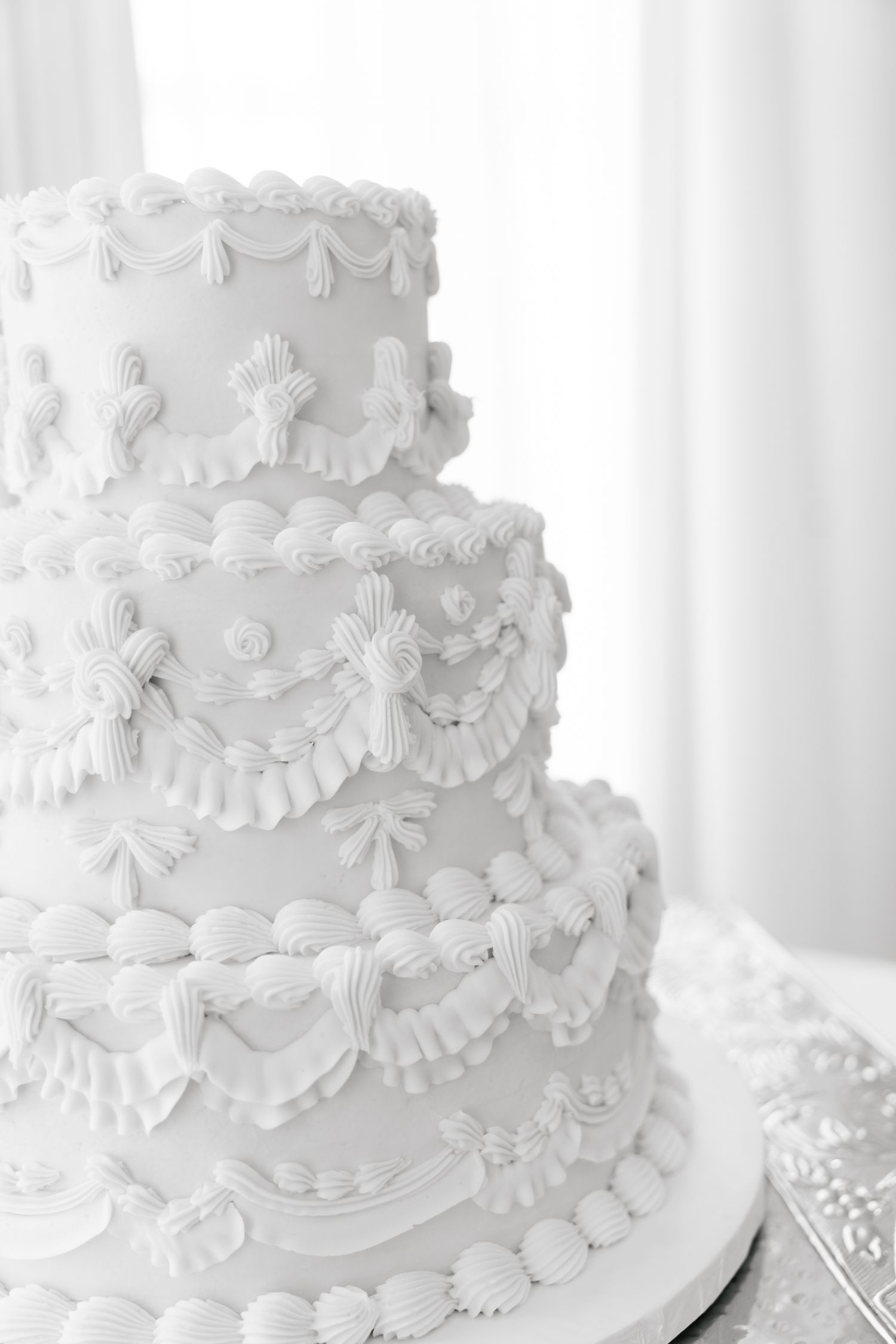 Elegant white wedding cake with intricate piping and delicate lace details.