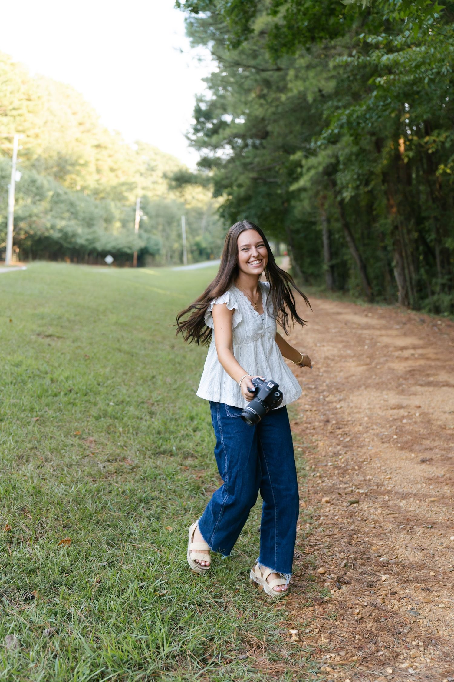 Playful poses captured along a dirt pathway bordered by trees and grass.