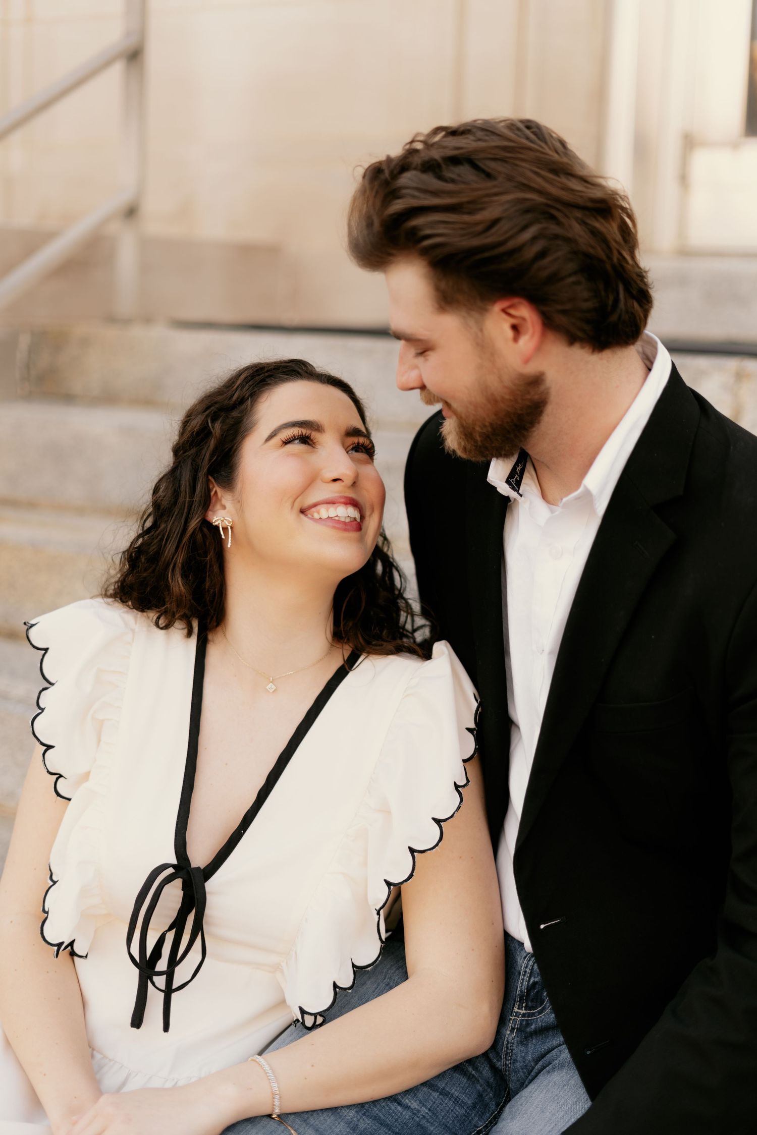 Couple in formal attire share intimate moments in an elegant architectural setting.