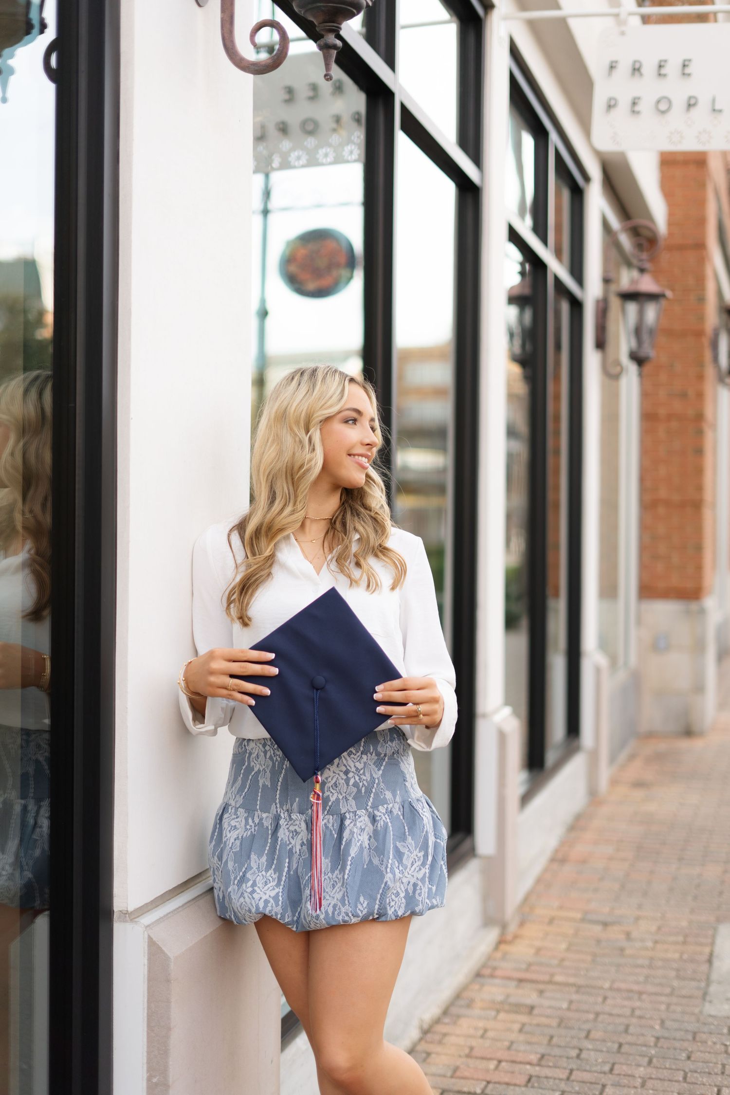 Person wearing navy romper posing against storefront windows.