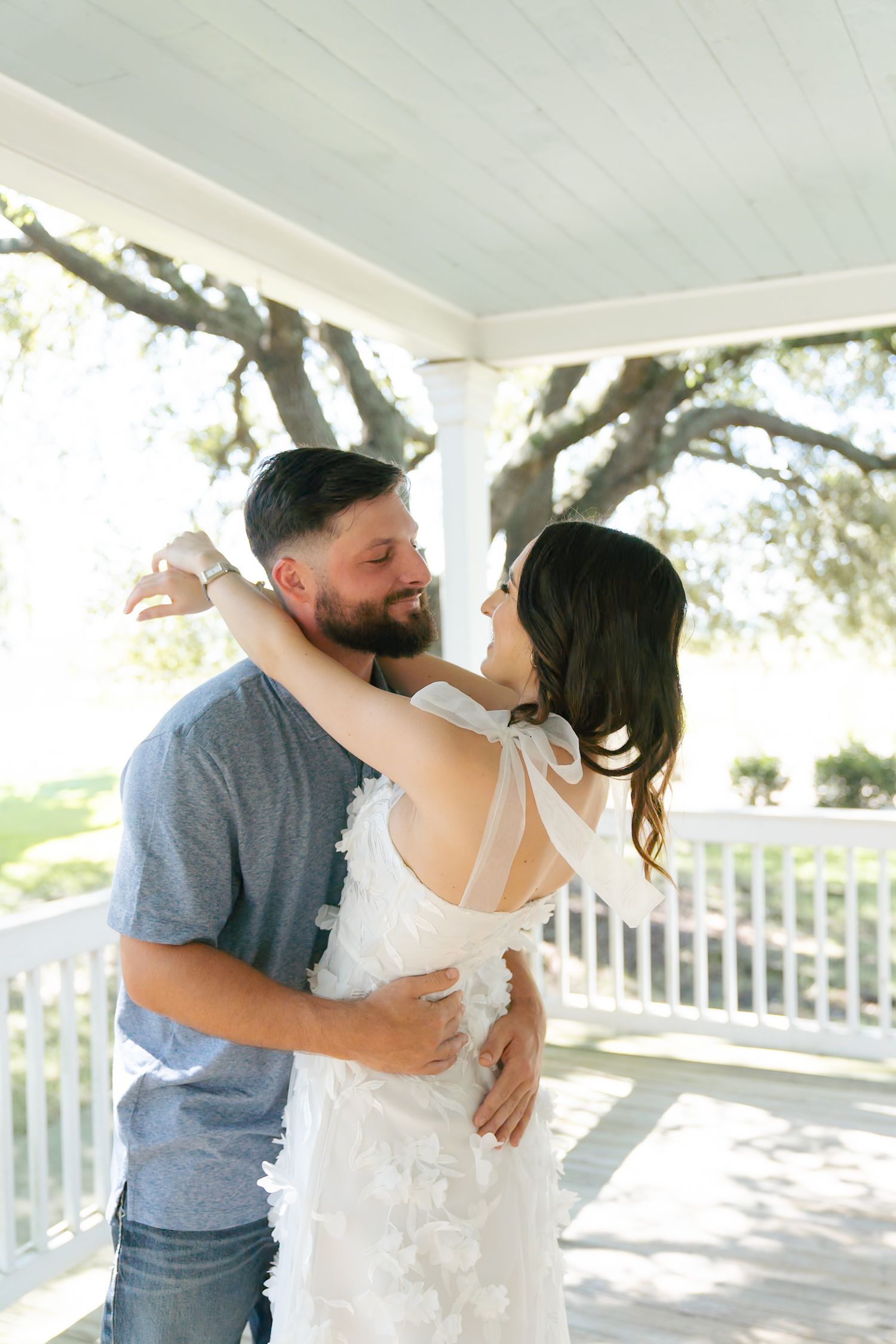 Couple embracing and dancing together on sunlit white porch.