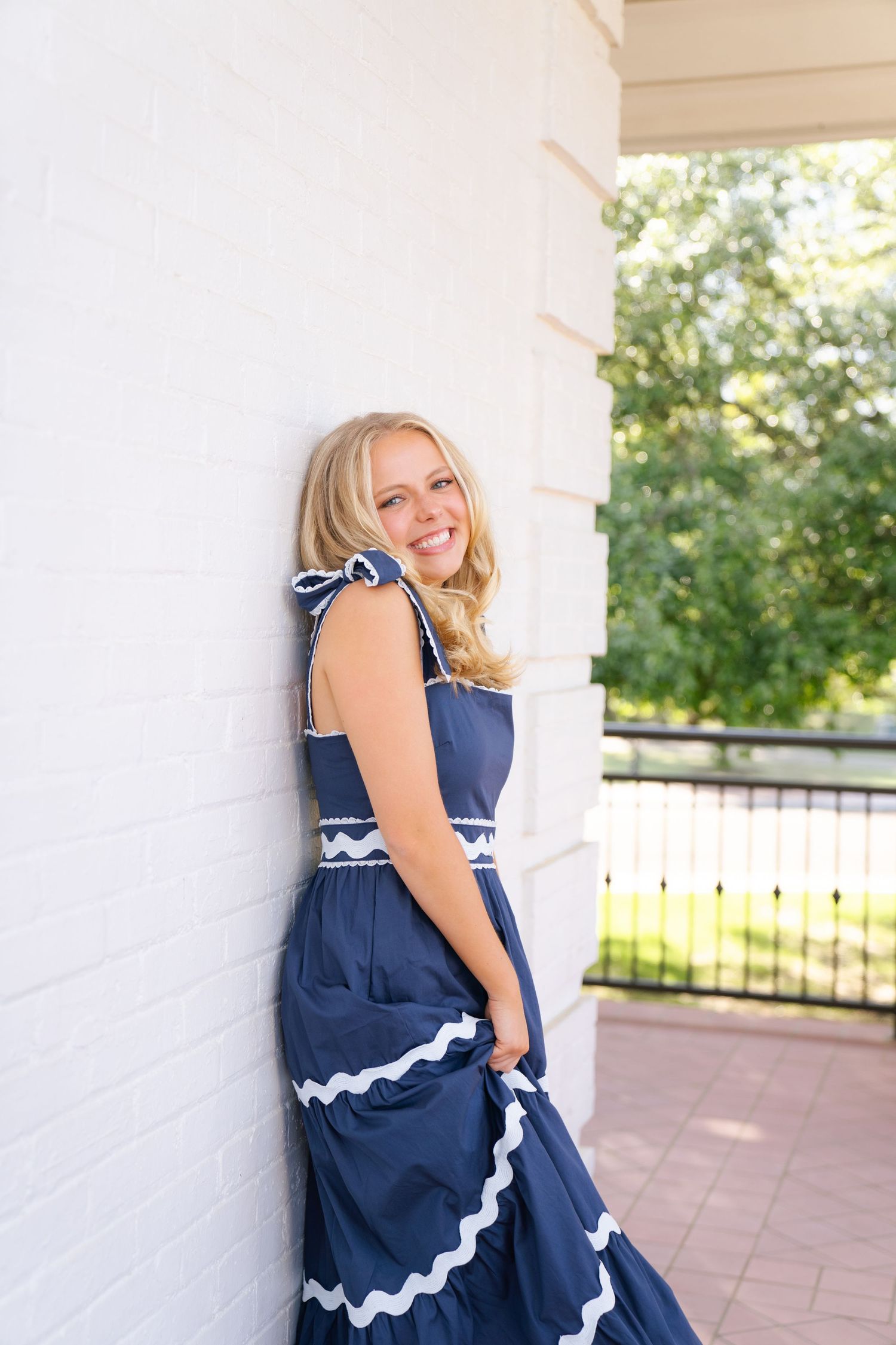 Portrait series against white walls wearing a navy blue dress with white trim.