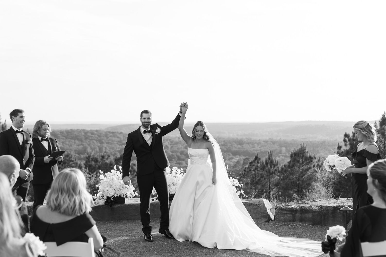 A joyous celebration at an outdoor wedding ceremony with scenic mountain views in the background.