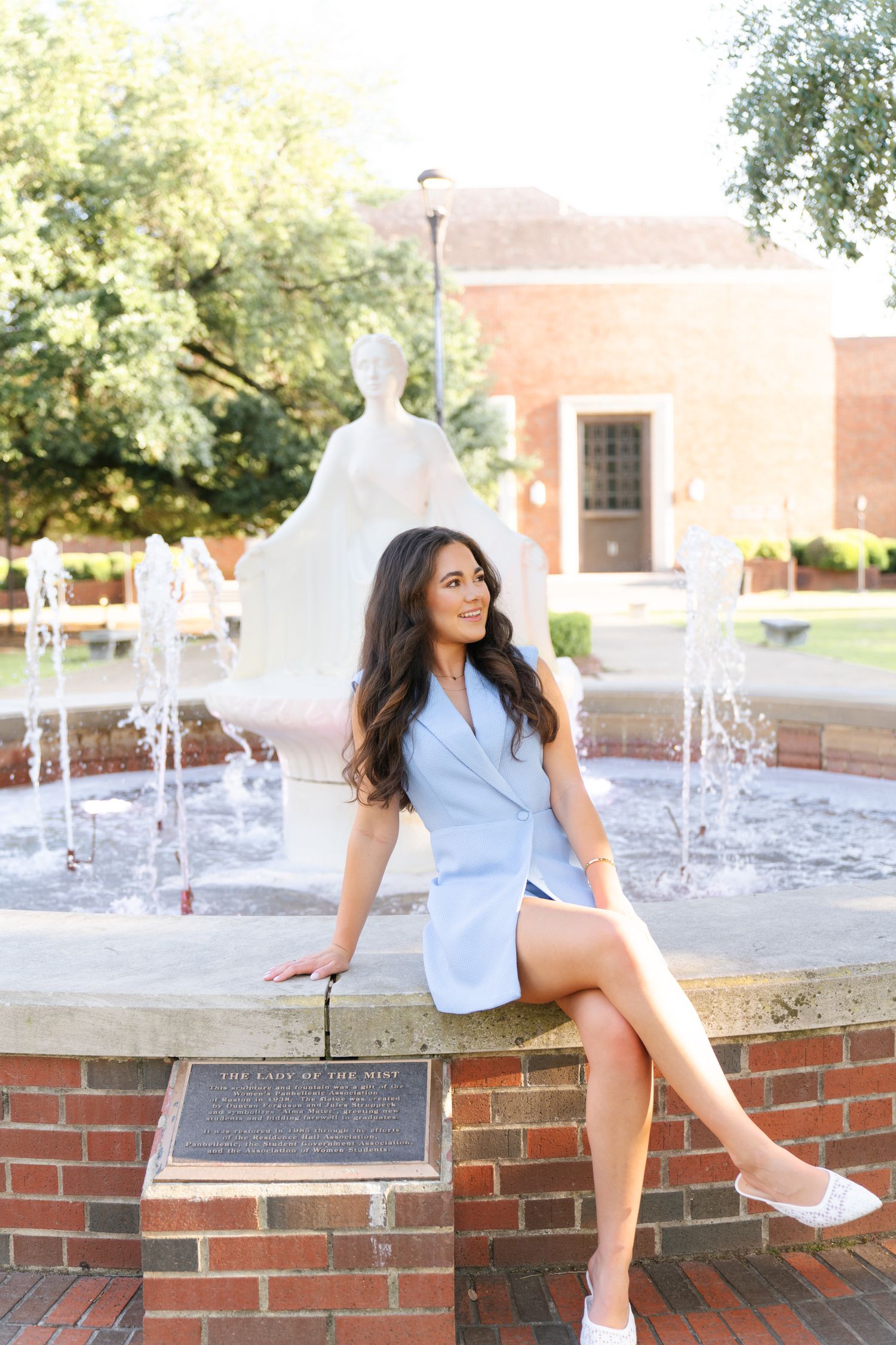 Artistic shots by a water fountain featuring brick architecture and white clothing.