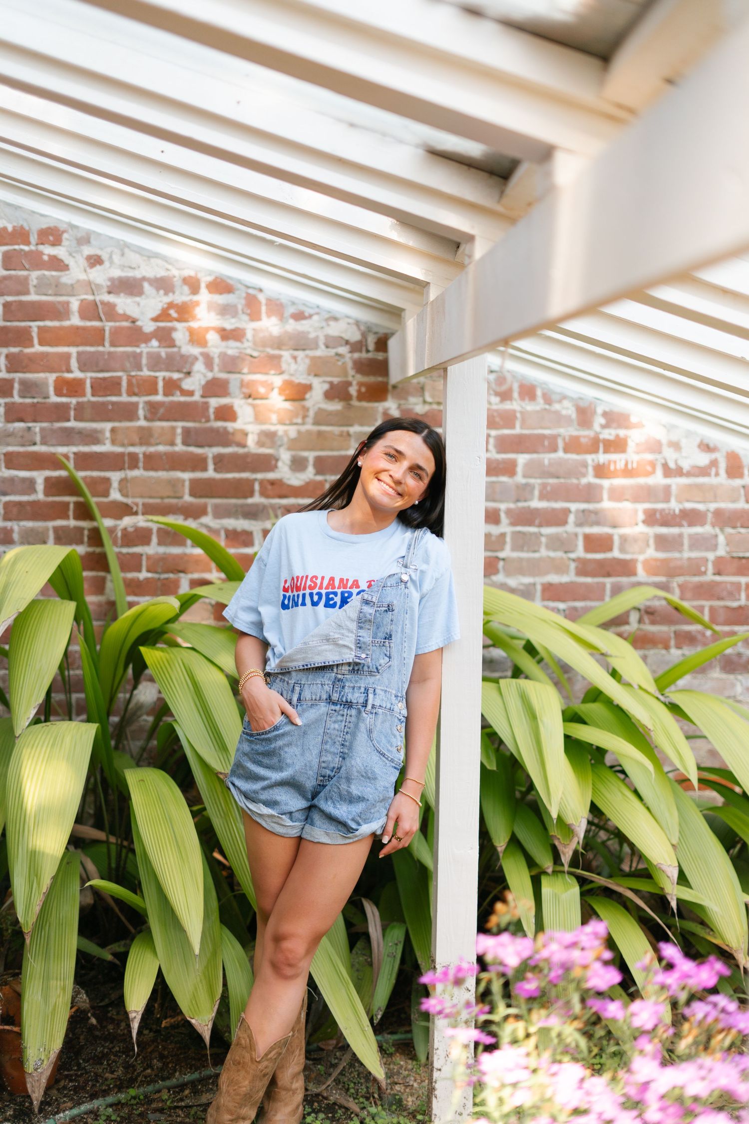 A series of outdoor photos showing someone posing against a brick wall with tropical plants and pink flowers.