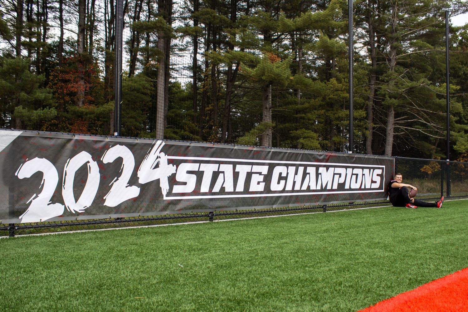 State championship banner displayed on football field fence with 2021 text.