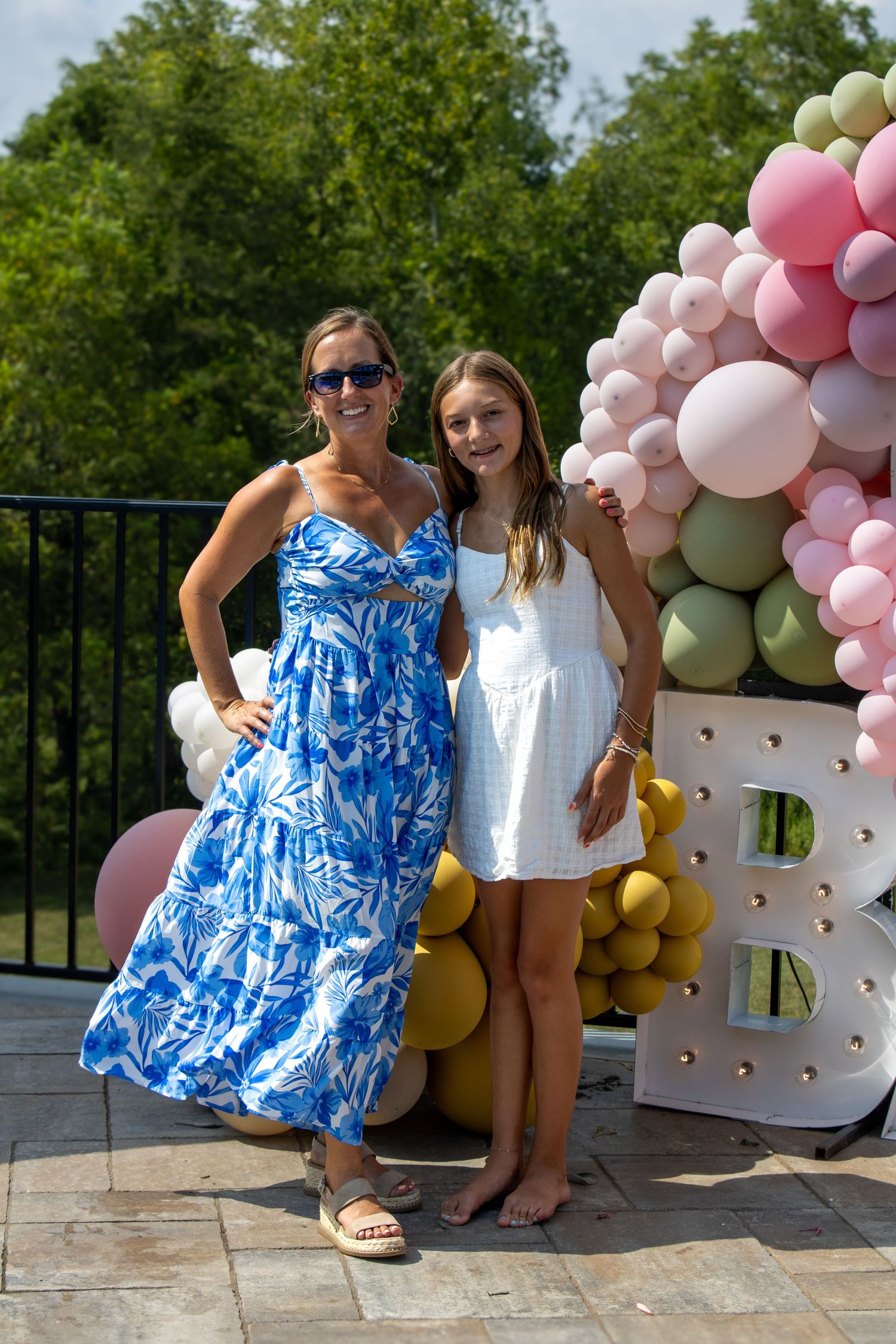 Summer party scene with balloon arch display in pink and gold tones on outdoor patio.