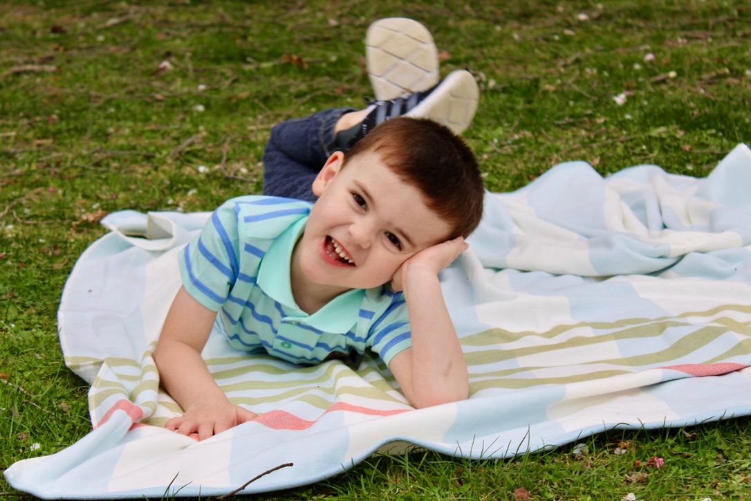 A preschooler lays on a pastel picnic blanket on a beautiful spring day.