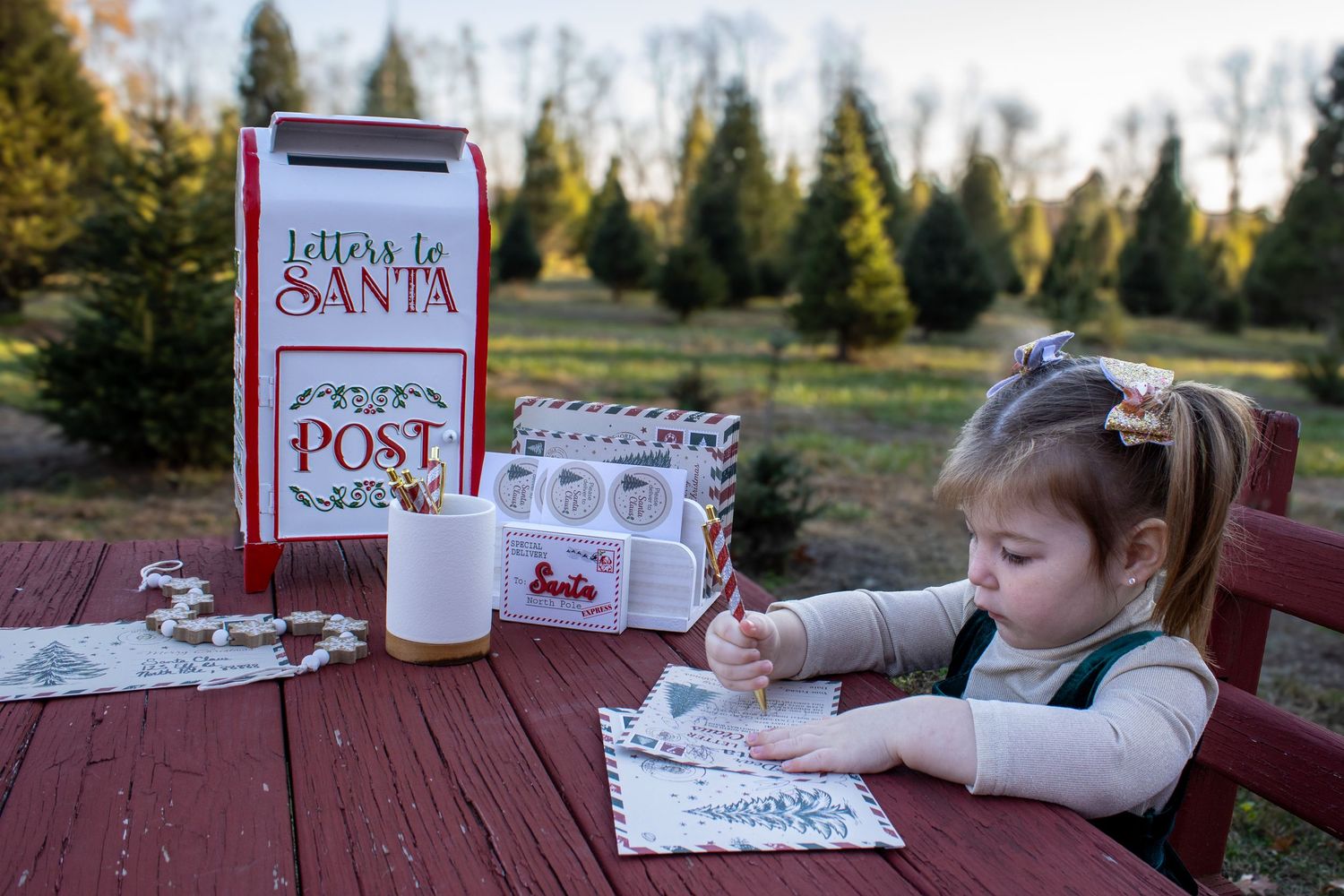 Writing letters to Santa at a red wooden table with holiday decorations.