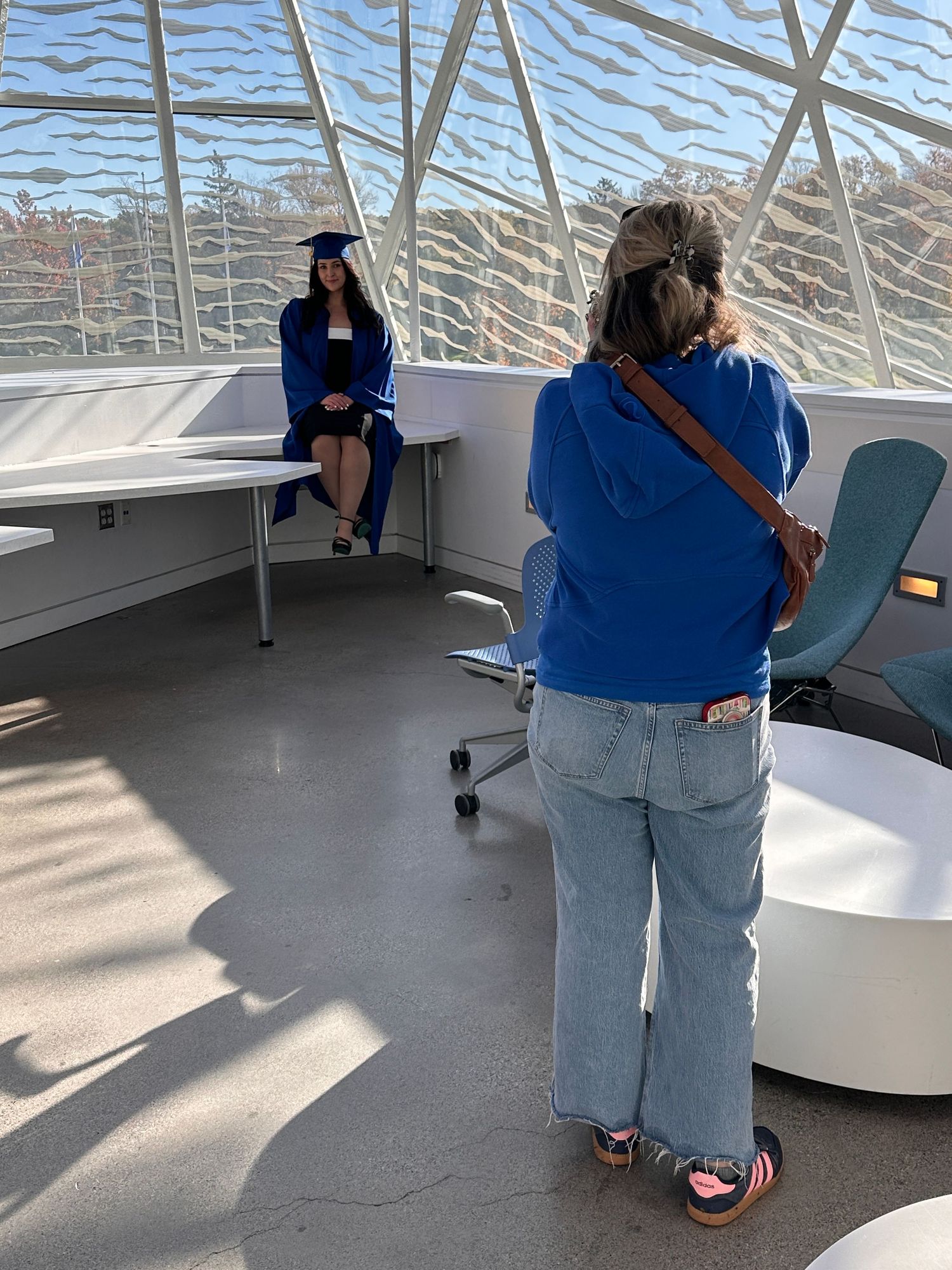 Person in blue shirt and jeans standing in modern room with geometric wall patterns.