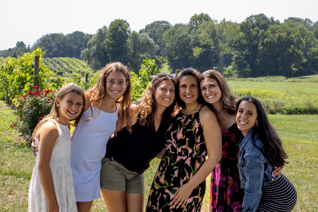 Group photo of friends gathered together in a sunny vineyard setting.