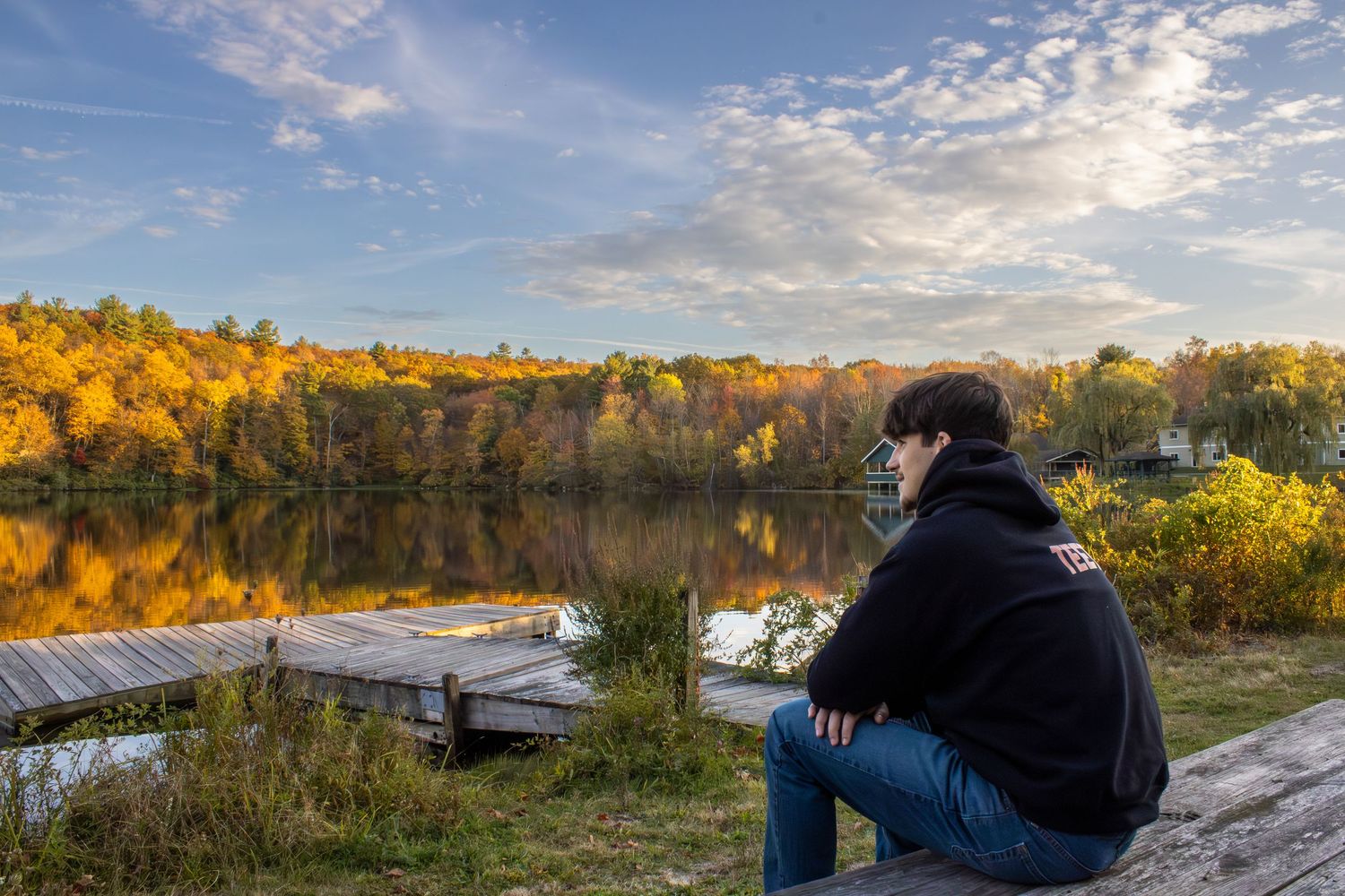 Beautiful autumn landscape with golden sunlight streaming through trees by a lake.