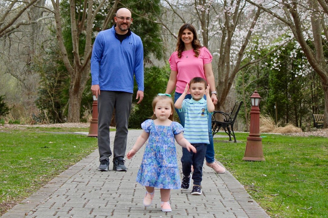 Family walking together on a stone path through a park during springtime.