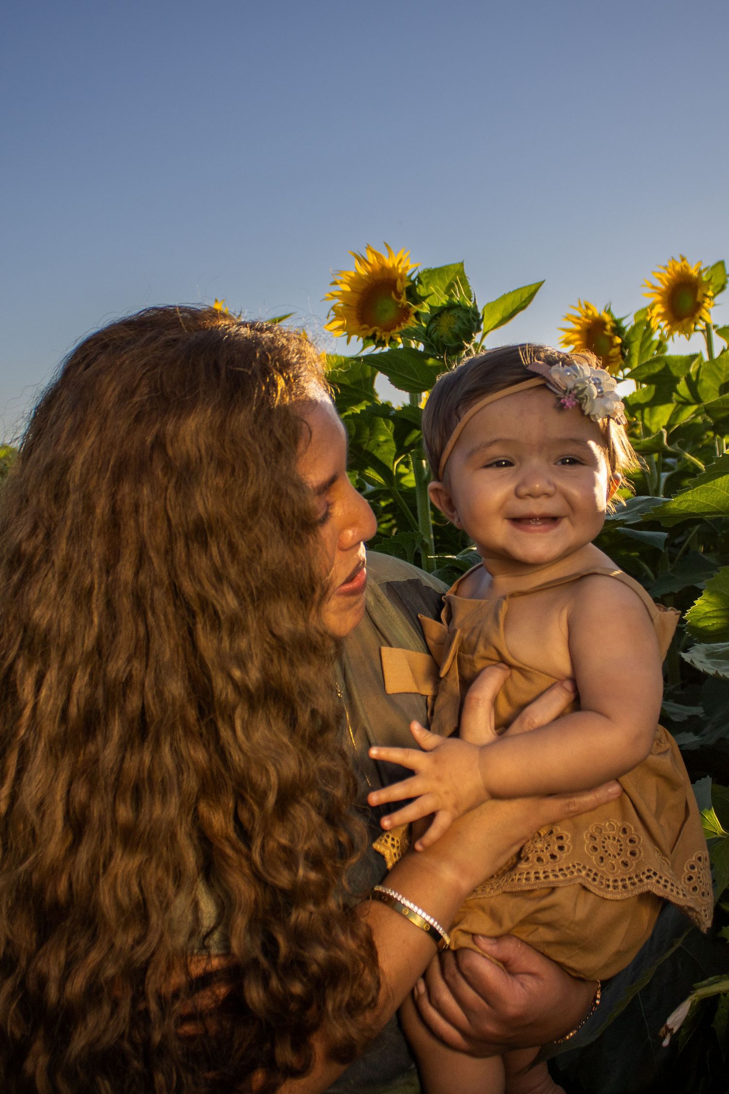 A tender moment captured in a sunflower field at golden hour.