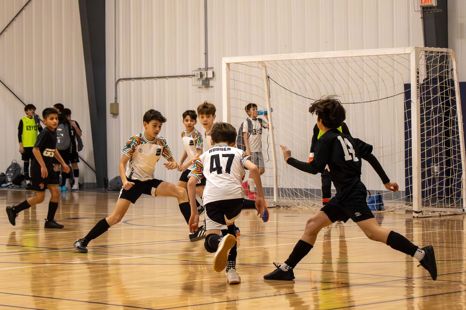 Indoor soccer match in progress with players spread across the court.
