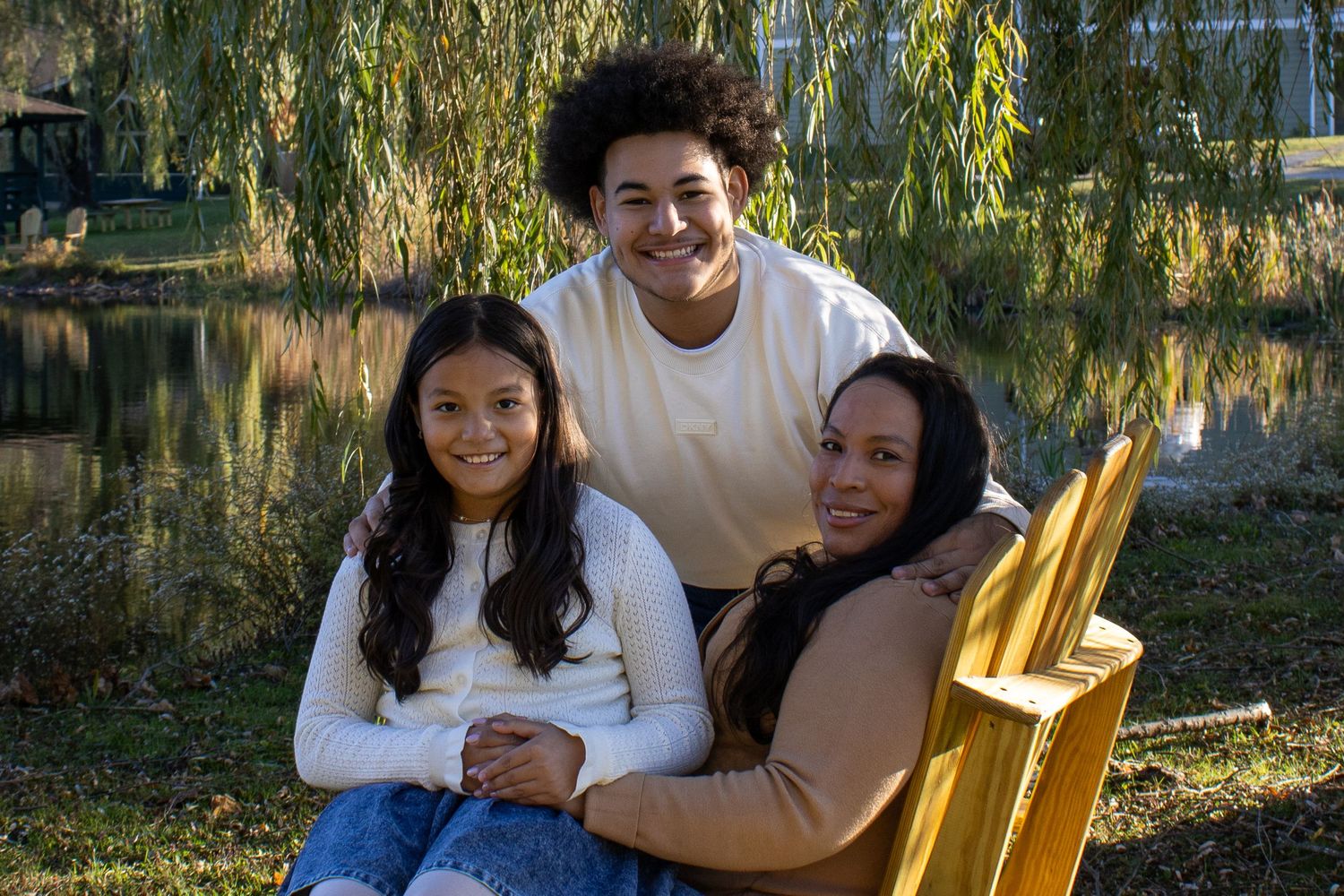 Family members sharing a warm moment on wooden chairs outdoors.