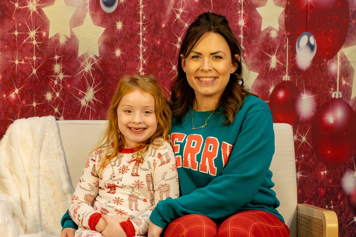 A festive family holiday photo session with red sparkly background and decorative stars and snowflakes.