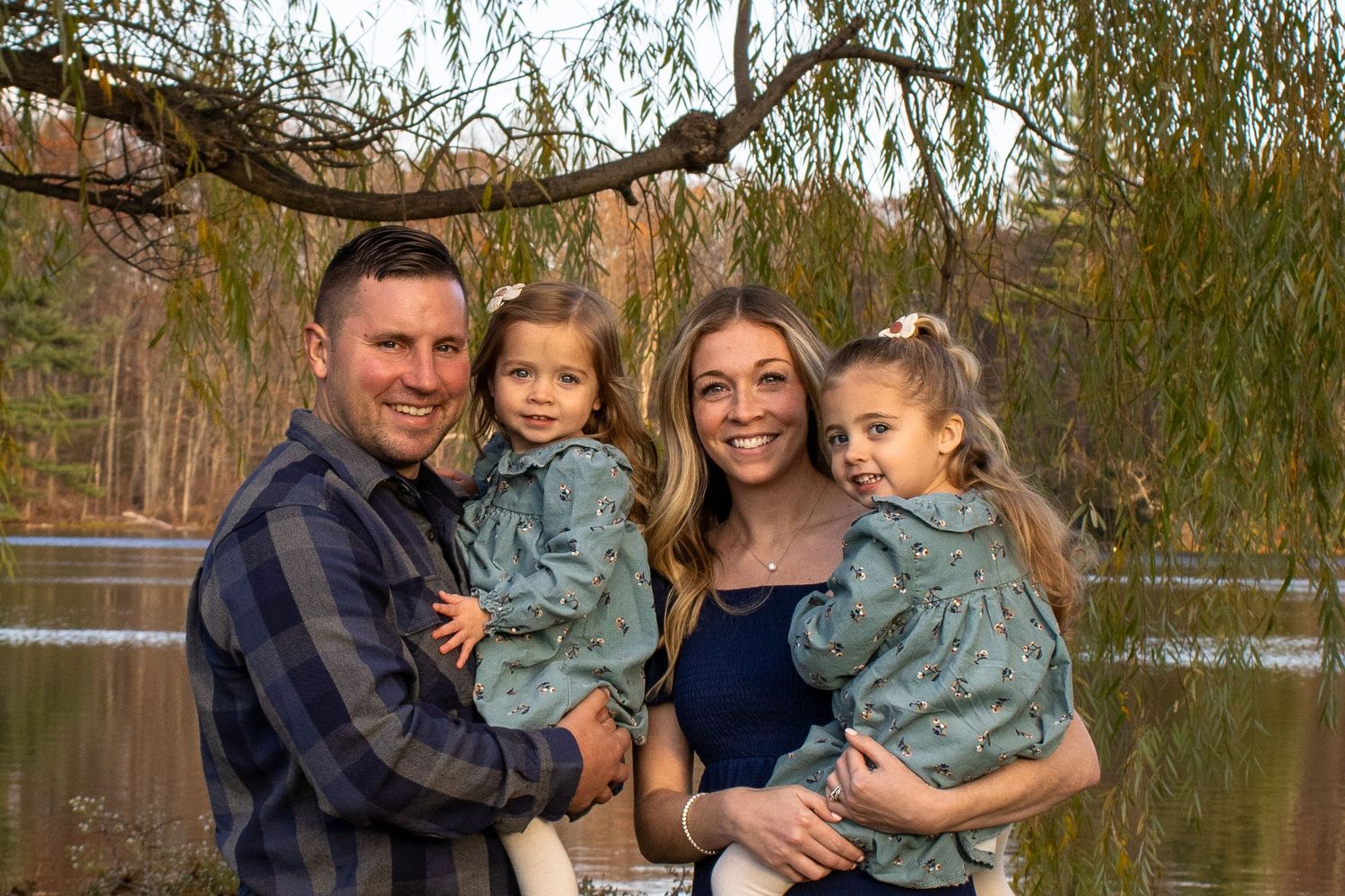 Family portrait session at lakeside during golden hour with fall foliage.