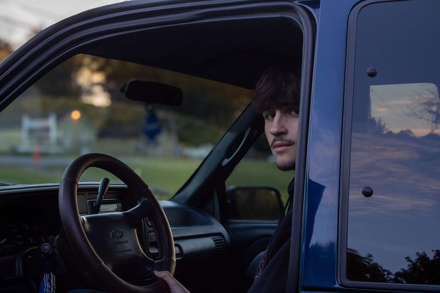 View from inside a dark blue vehicle looking out at sunset.