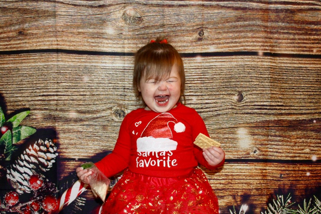 A toddler girl is positively elated during her Christmas portraits.