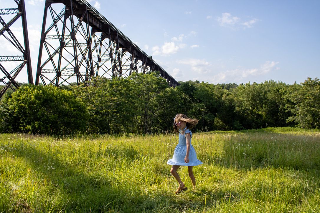 A young girl twirls in the field beneath the Moodna Viaduct on a beautiful summer day.
