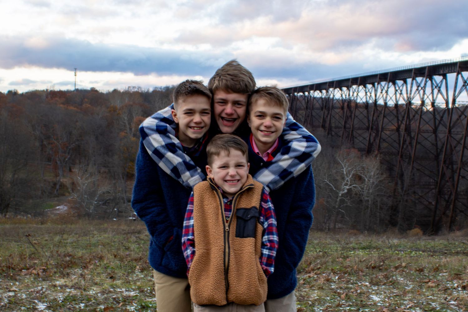 Casual family gathering in front of rustic bridge during sunset.
