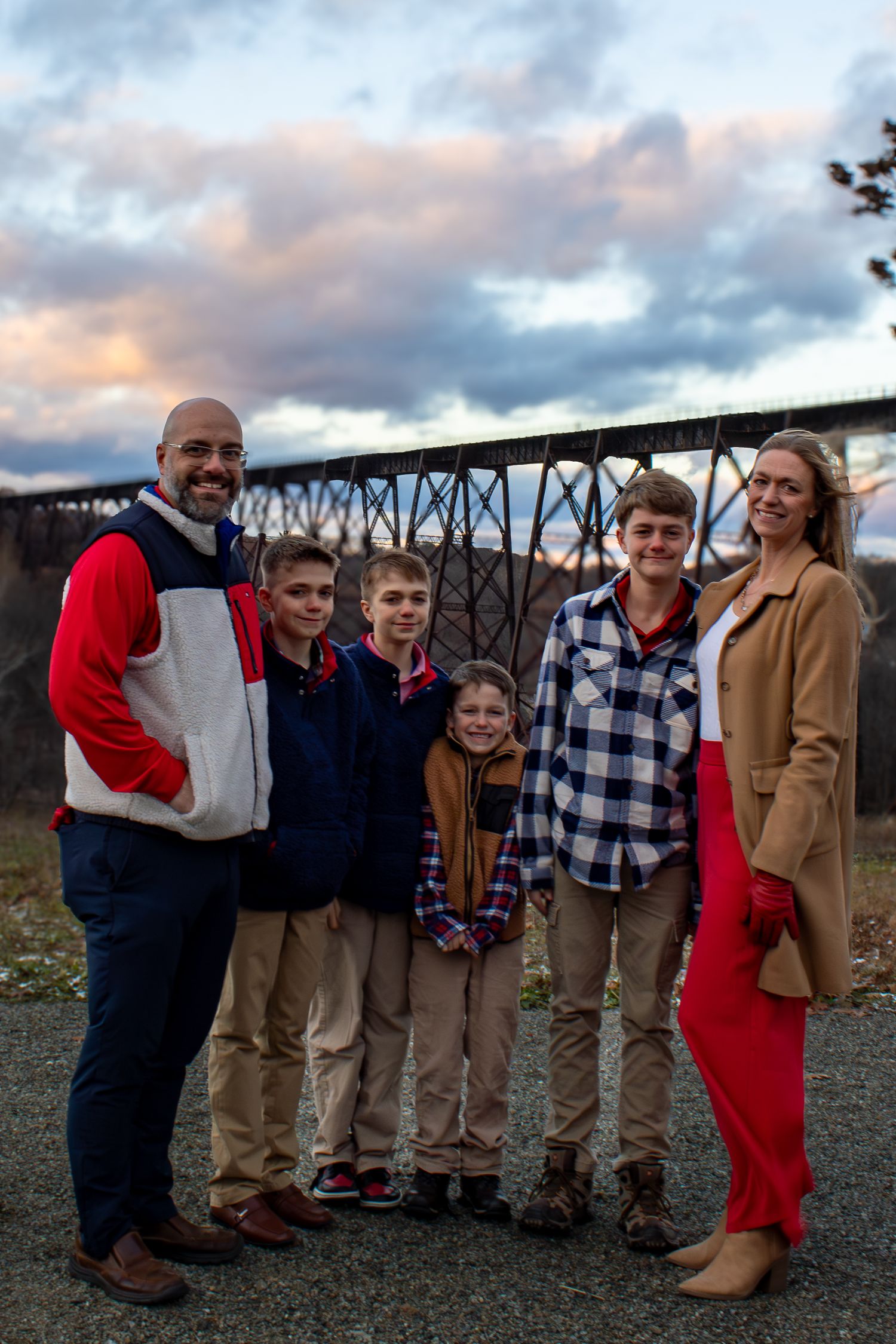 Group photo of family members against metal bridge structure at dusk.