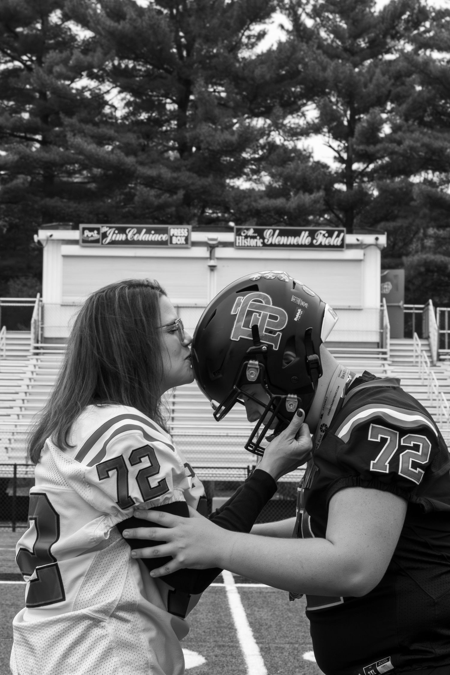 Two football players in black and white jerseys share an intimate moment on the field.