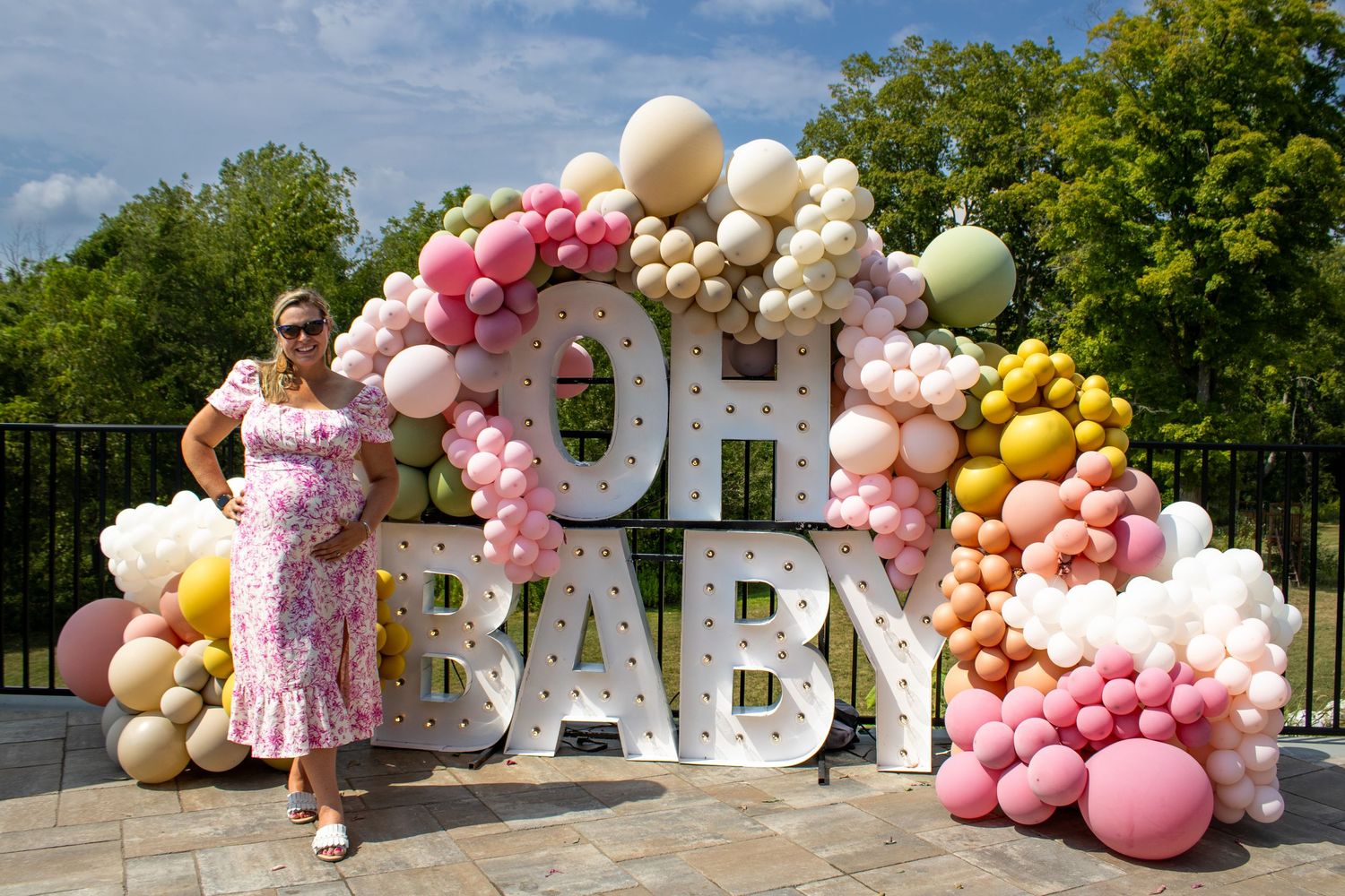 Decorative balloon arch with pastel colors and white letters spelling BABY outdoors.